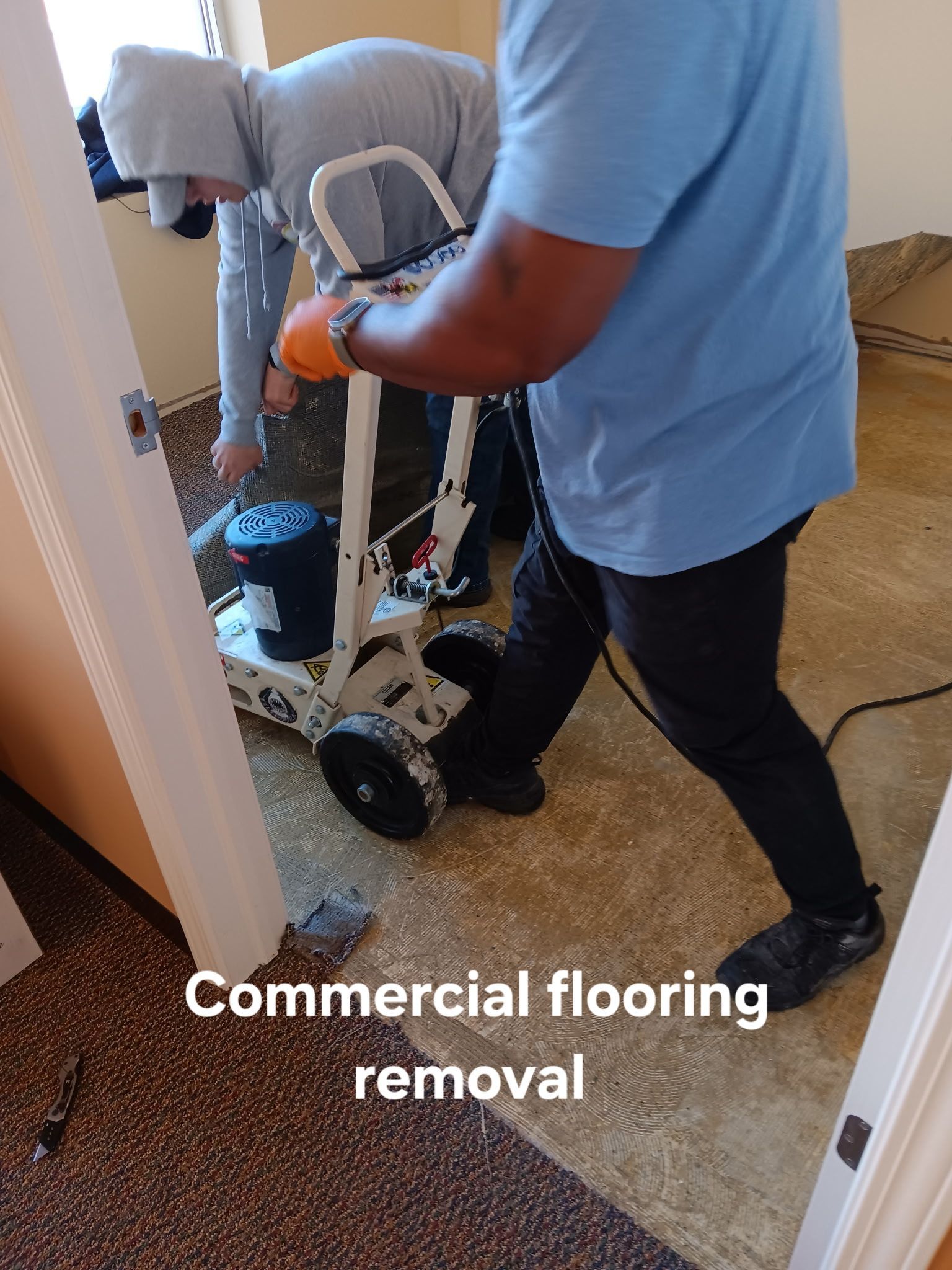 Worker removing commercial flooring with a floor machine in an indoor room