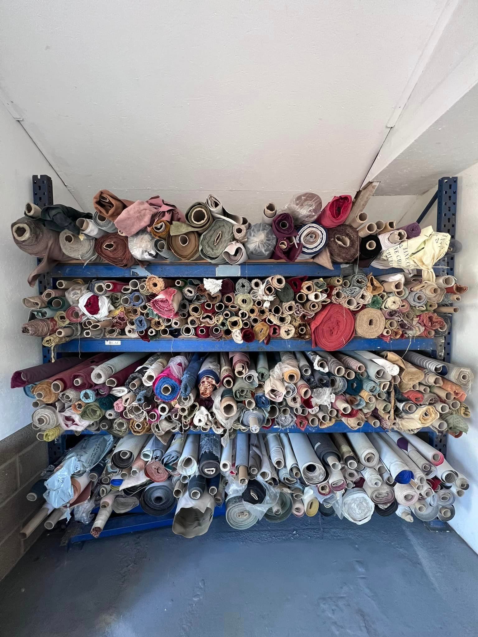 A room filled with lots of rolls of fabric on shelves.