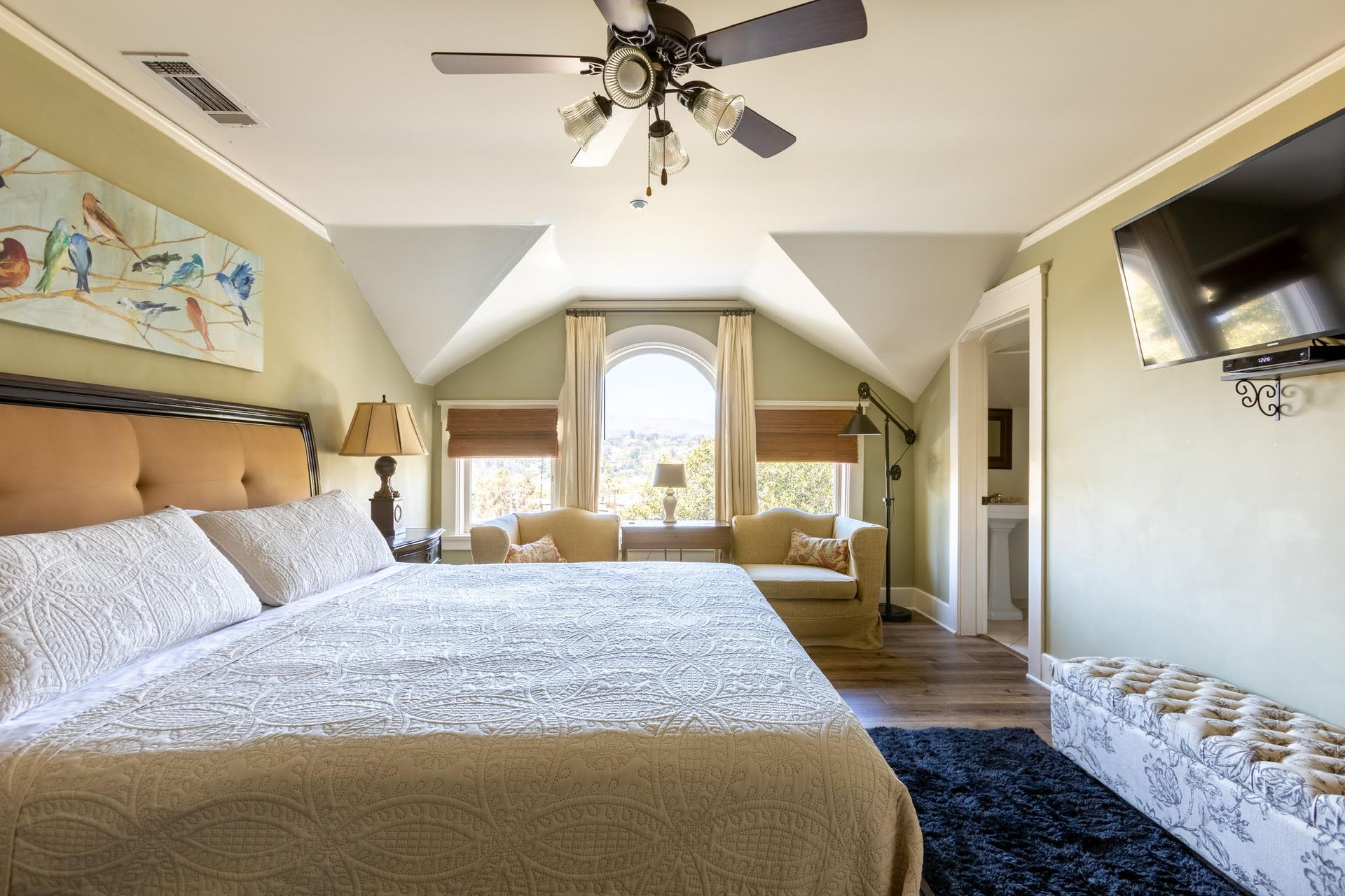 A bedroom at Arroyo Vista Inn with king sized bed, mounted TV, and sitting area.