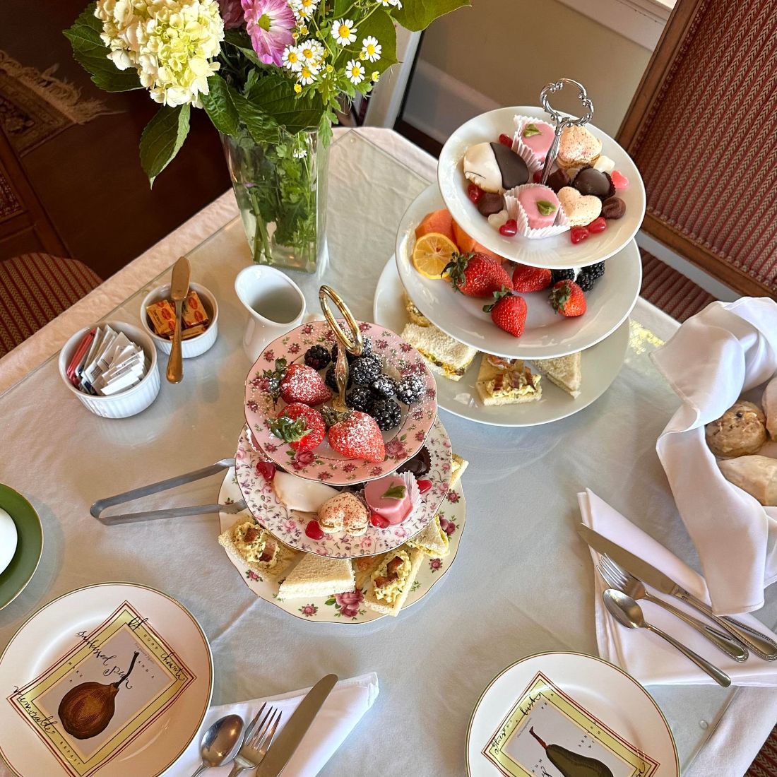 A table topped with plates of food and a tower of desserts.