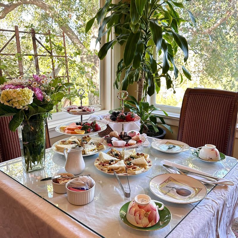 A table topped with plates of food and a vase of flowers.