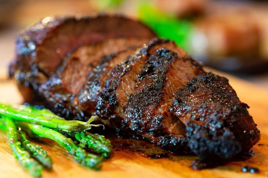A close up of a steak and asparagus on a cutting board.