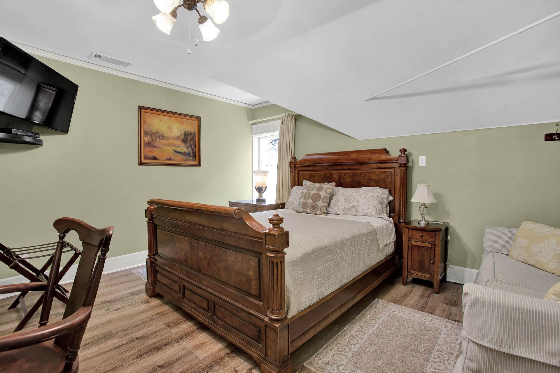 A bedroom with a bed , nightstand , chair and television.
