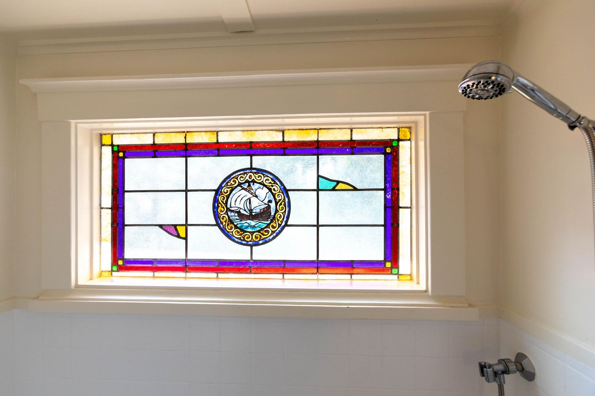 A bathroom with a stained glass window and a shower head