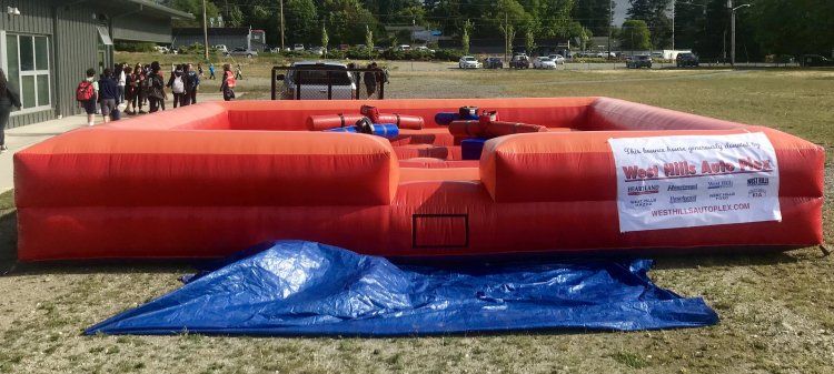 A large red inflatable couch is sitting on top of a blue tarp in a field.