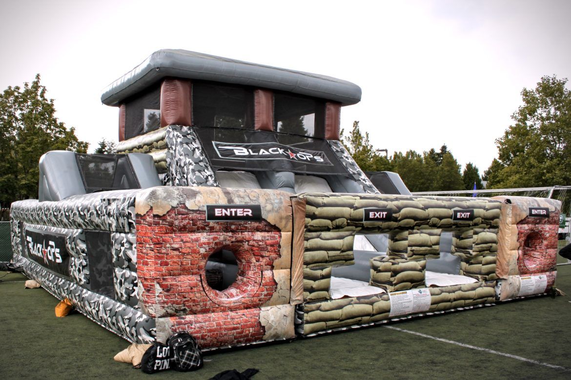 A large inflatable obstacle course is sitting on top of a soccer field.