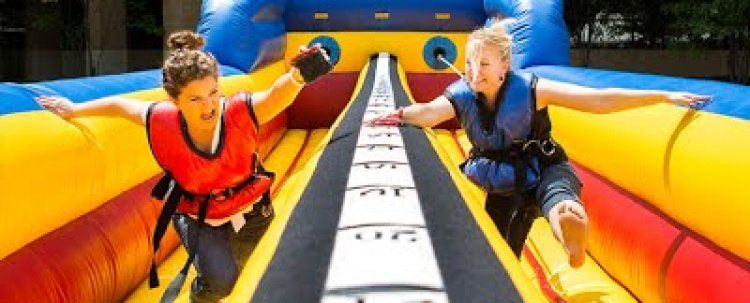 Two people are playing a game on an inflatable slide.