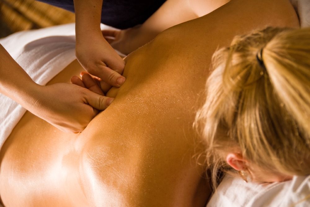 Massage therapist applying back massage in a spa setting