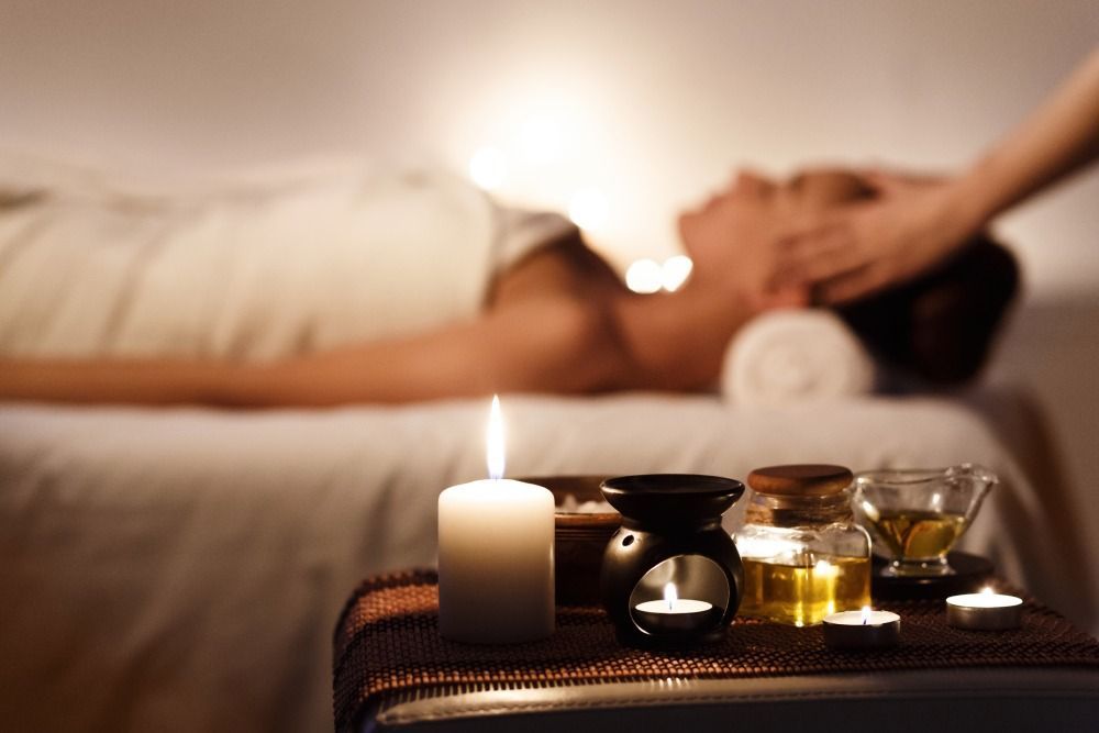 Lit candle and spa oils on a tray in a softly blurred massage room