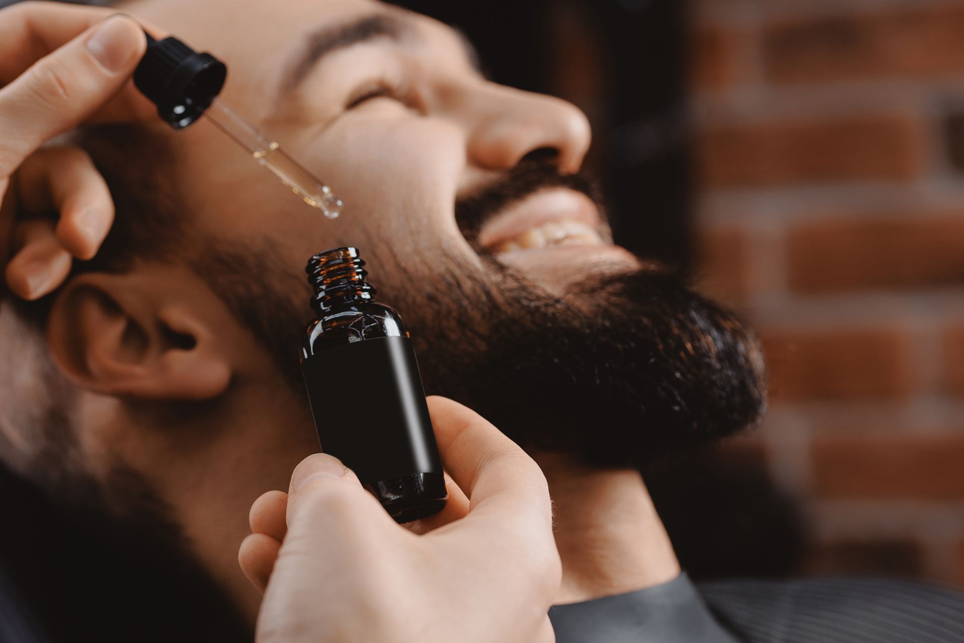 A man is applying beard oil to his beard.