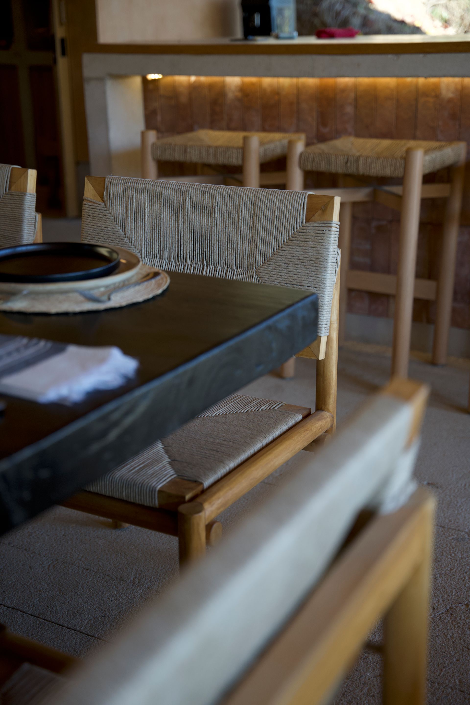 Cozy restaurant table with woven chairs and warm wood bar seating