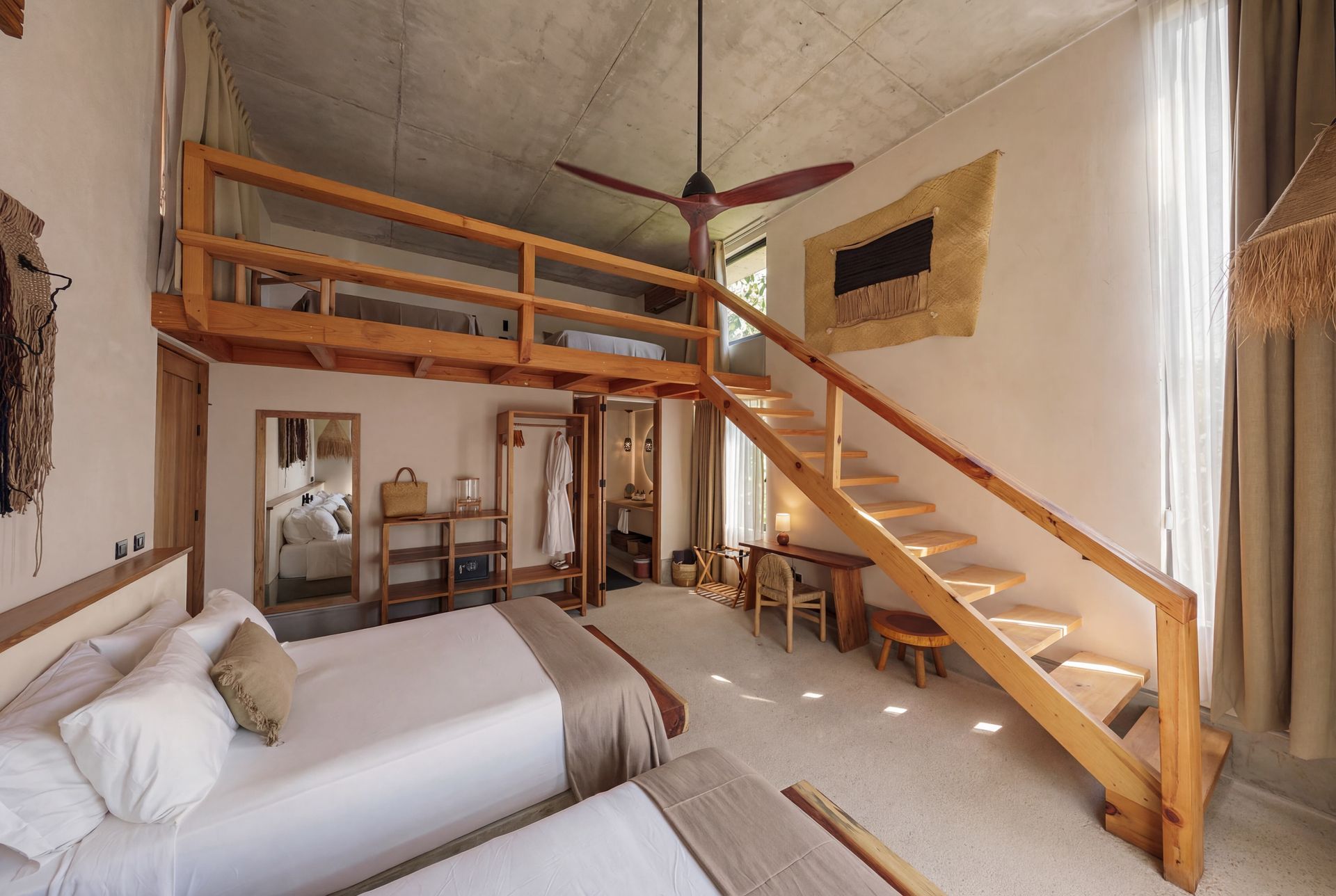 Loft bedroom with two beds, wooden staircase, and bright sloped ceiling