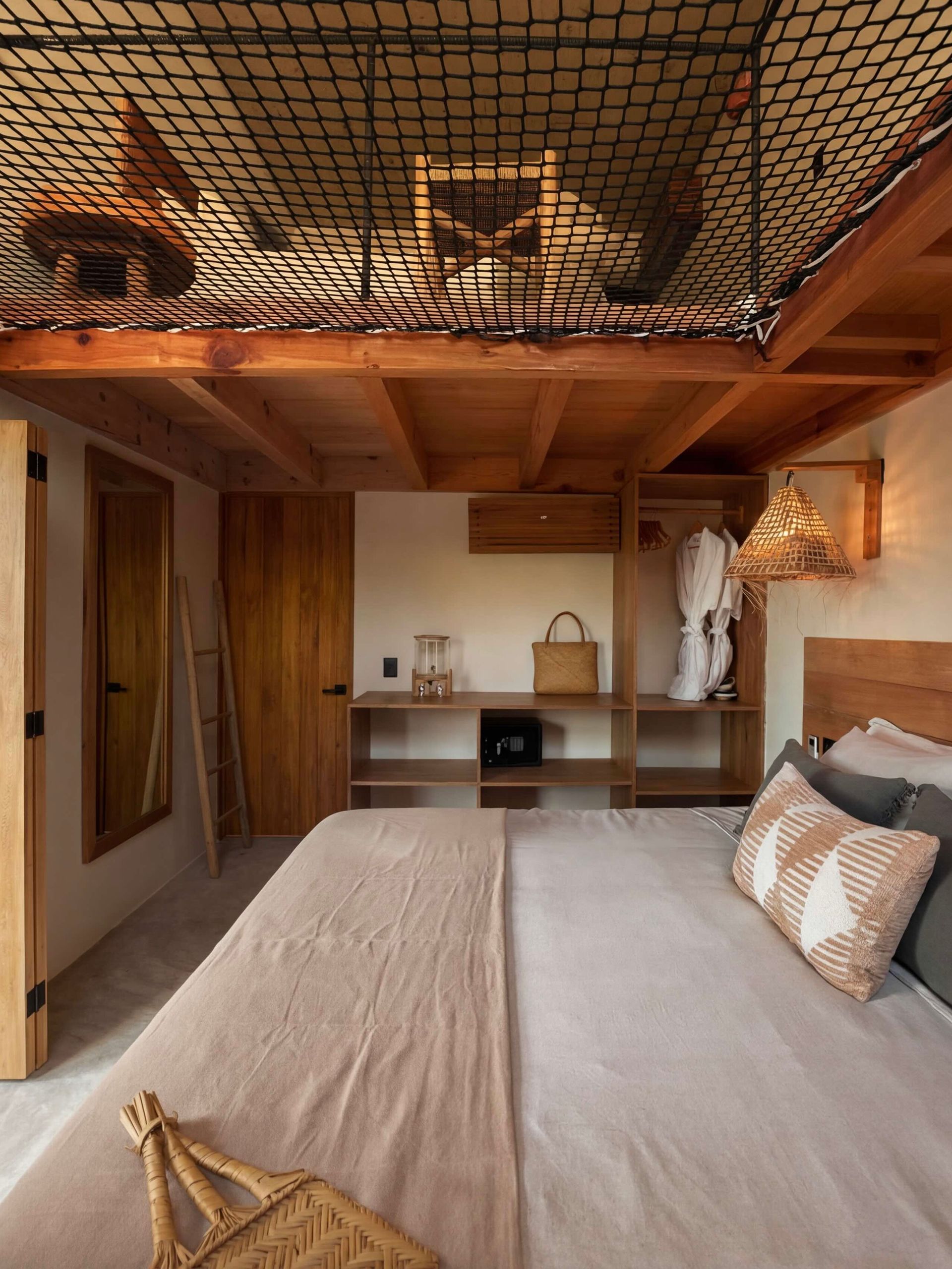 Cozy wooden loft bedroom with a netted ceiling, bed, desk nook, and warm natural light.