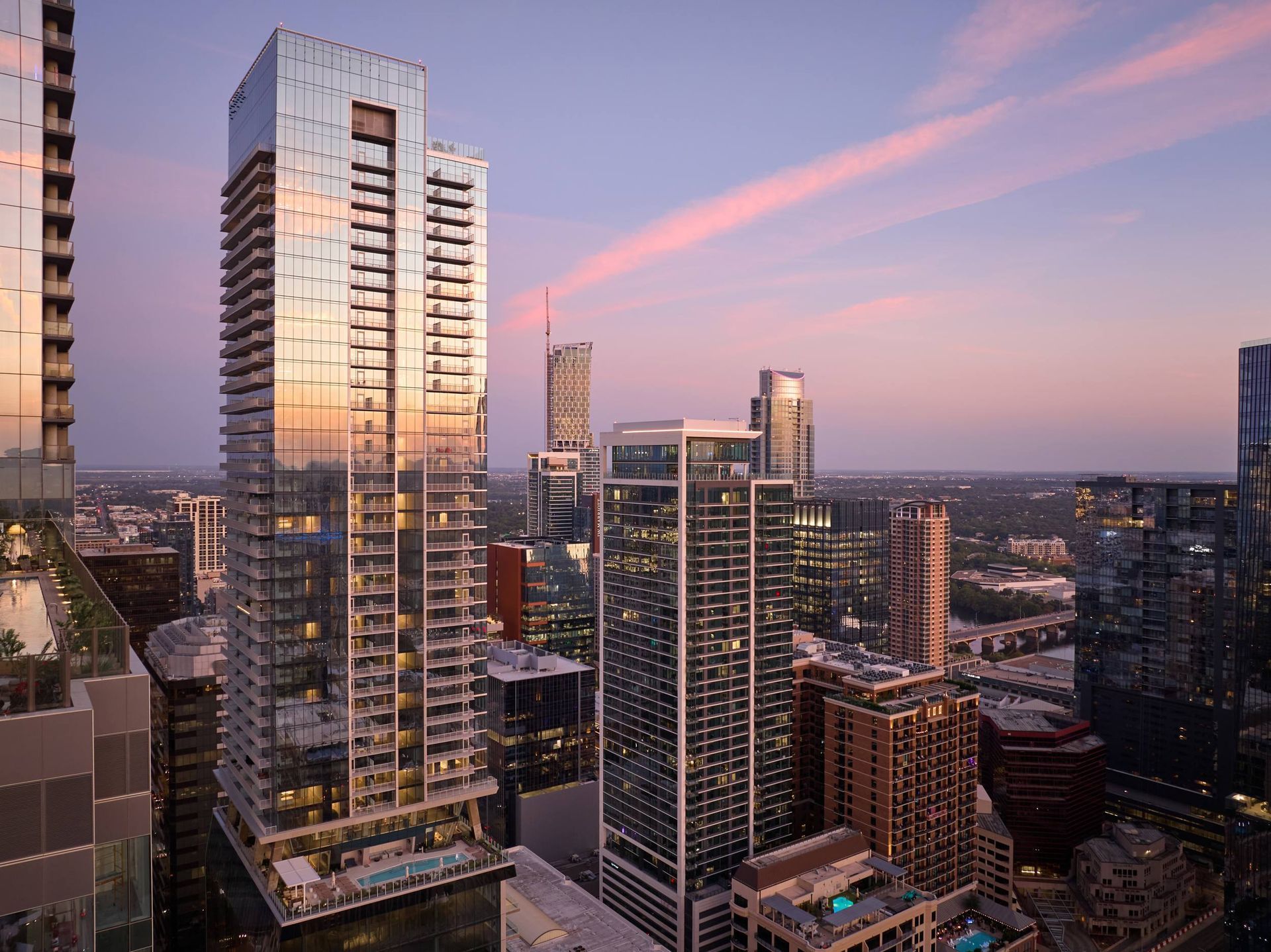 City skyline at dusk with tall glass buildings reflecting the colorful sky.
