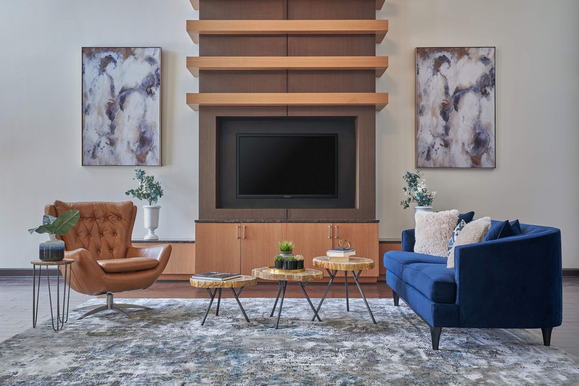 Living room with blue sofa, brown armchair, TV, and artwork.