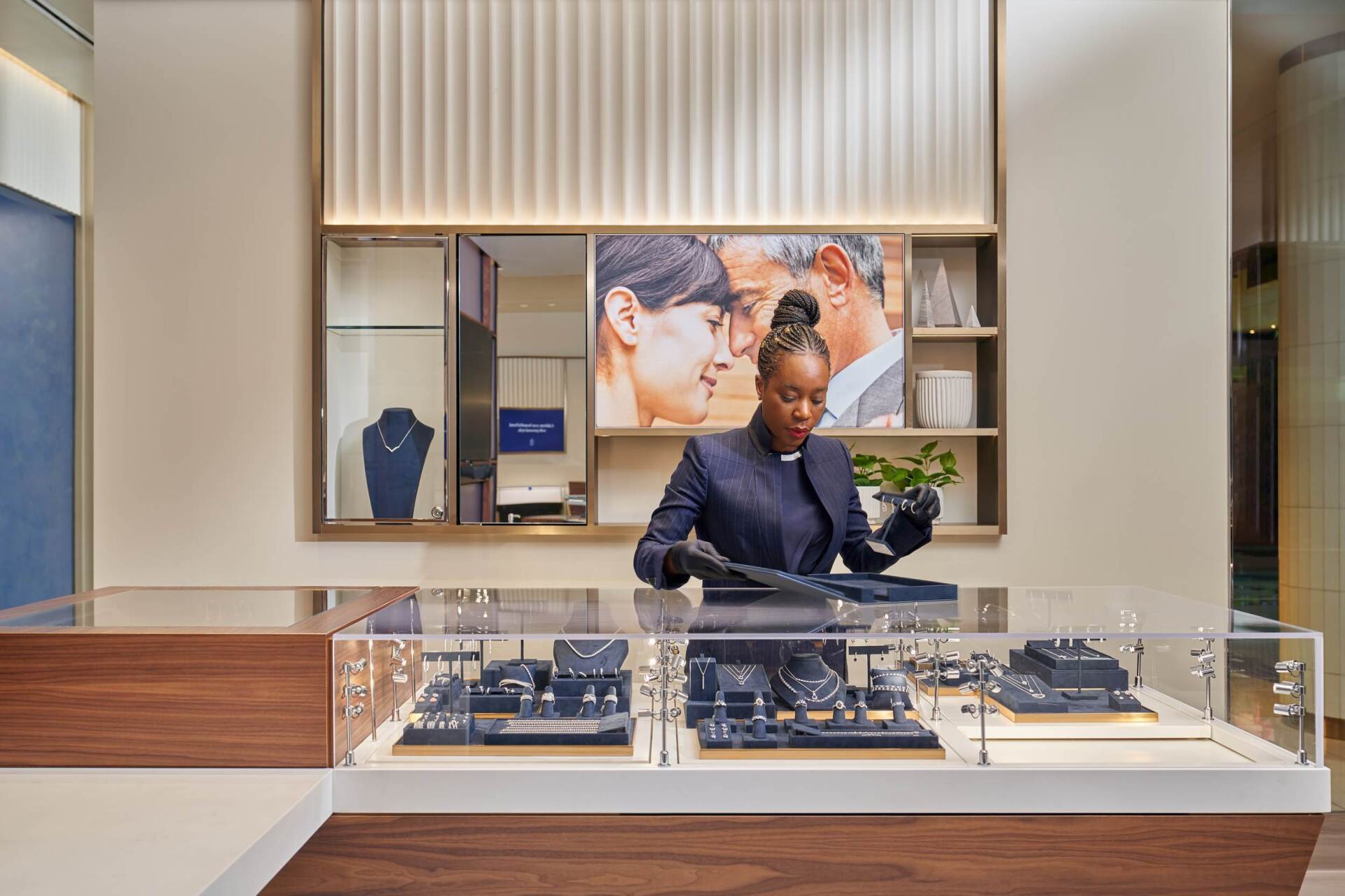 Jewelry store display with a person in uniform arranging items.