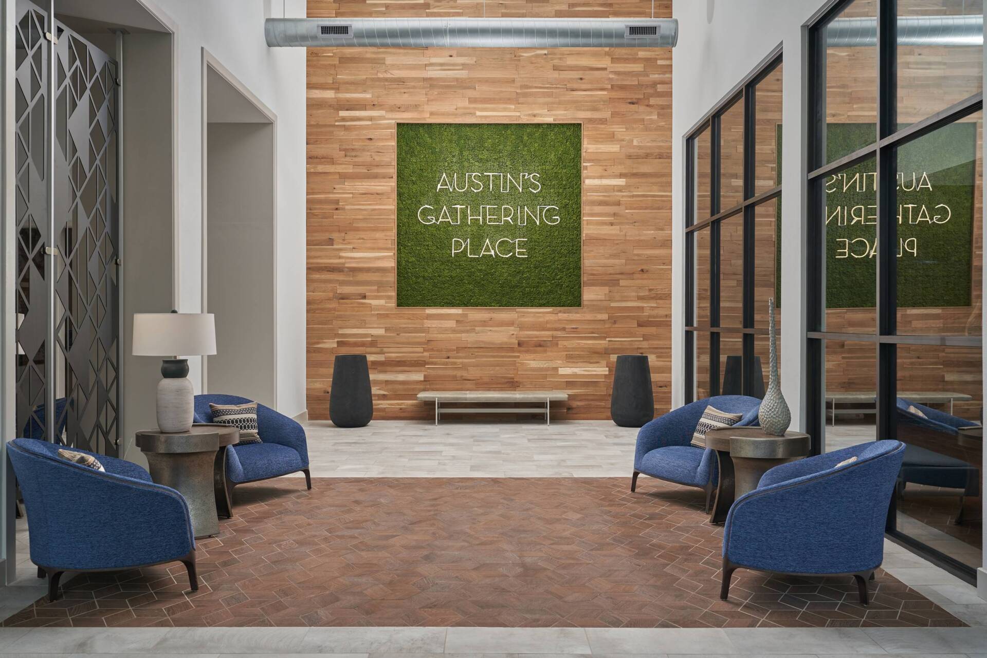 Lobby with seating area, wooden wall with moss art, and glass windows. 