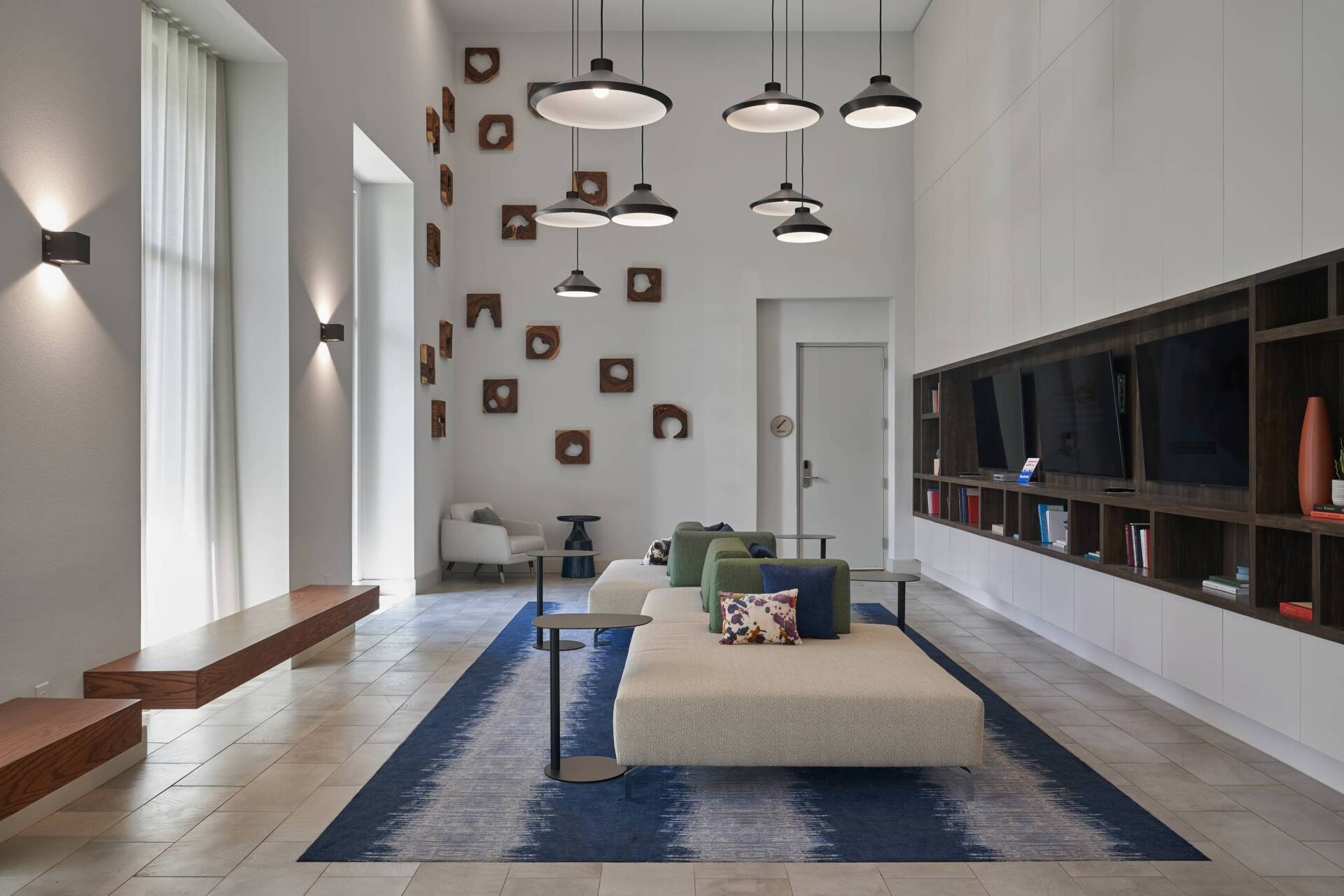 Modern lounge with pendant lights, a seating area, built-in shelving, and a decorative wall.