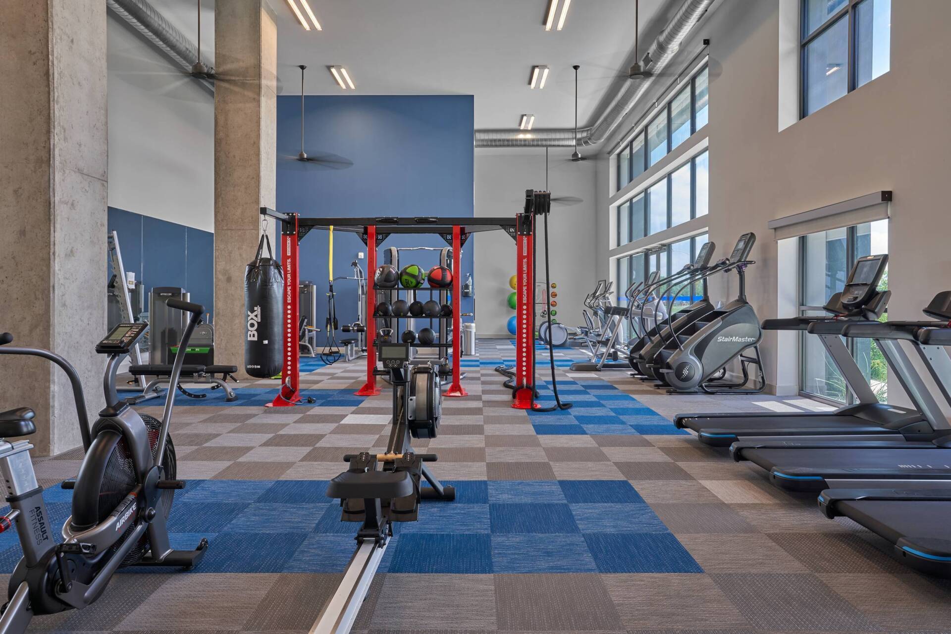 Gym interior with exercise equipment on blue and gray checkered flooring.