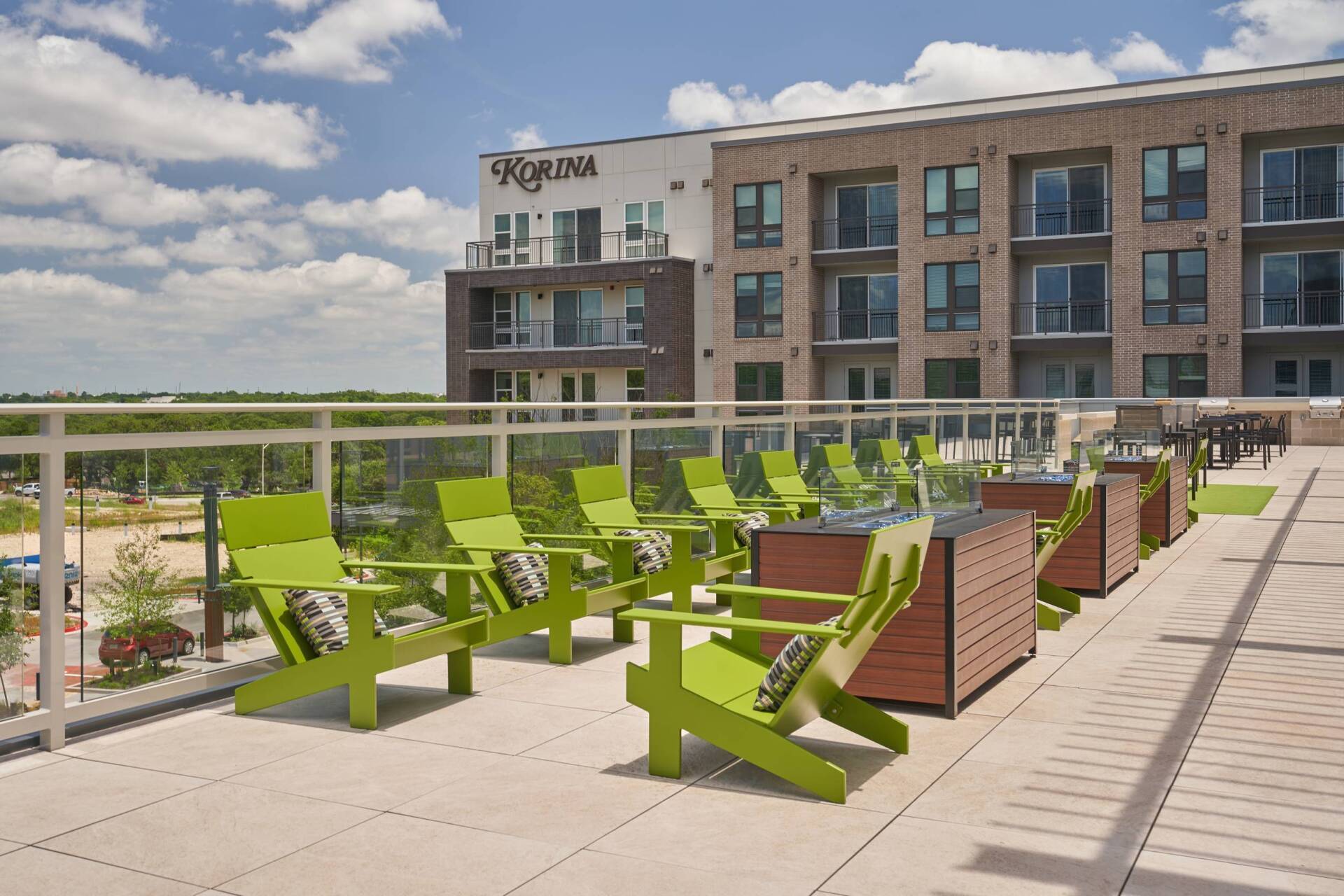 Rooftop patio with green chairs and a building in the background on a sunny day.