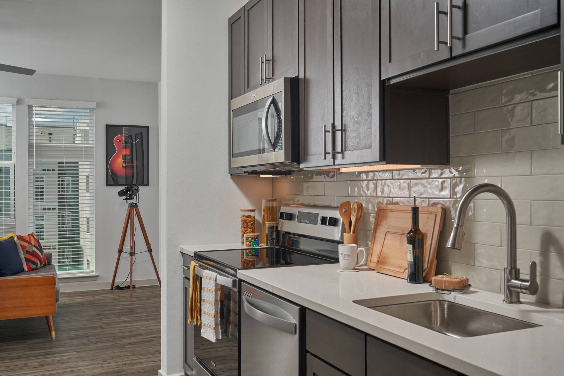 Modern kitchen with dark cabinets, stainless steel appliances, and a white countertop.