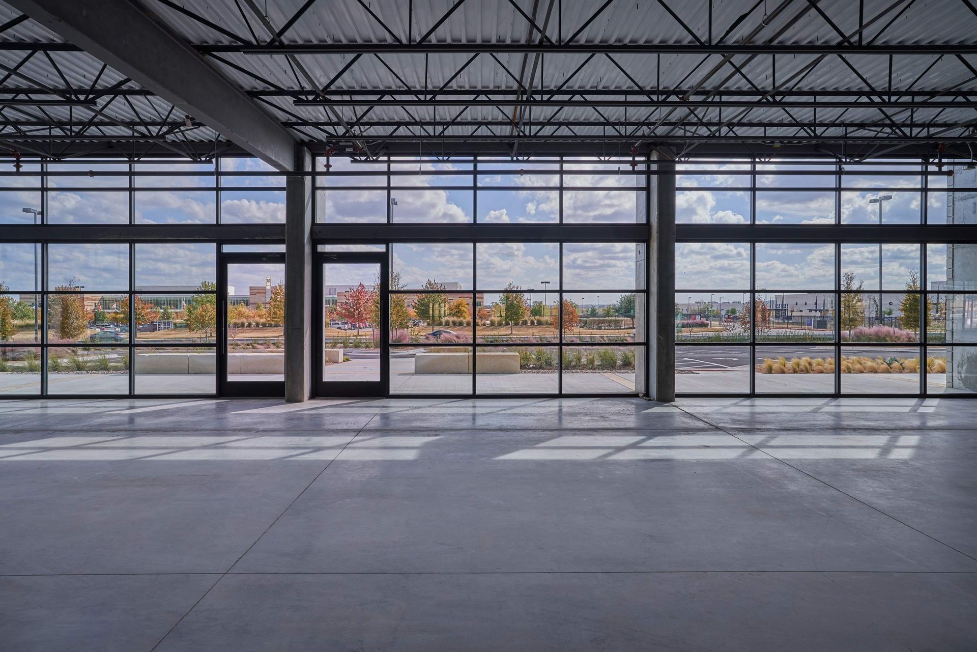 Interior view of a modern building with large glass windows overlooking an outdoor landscape.
