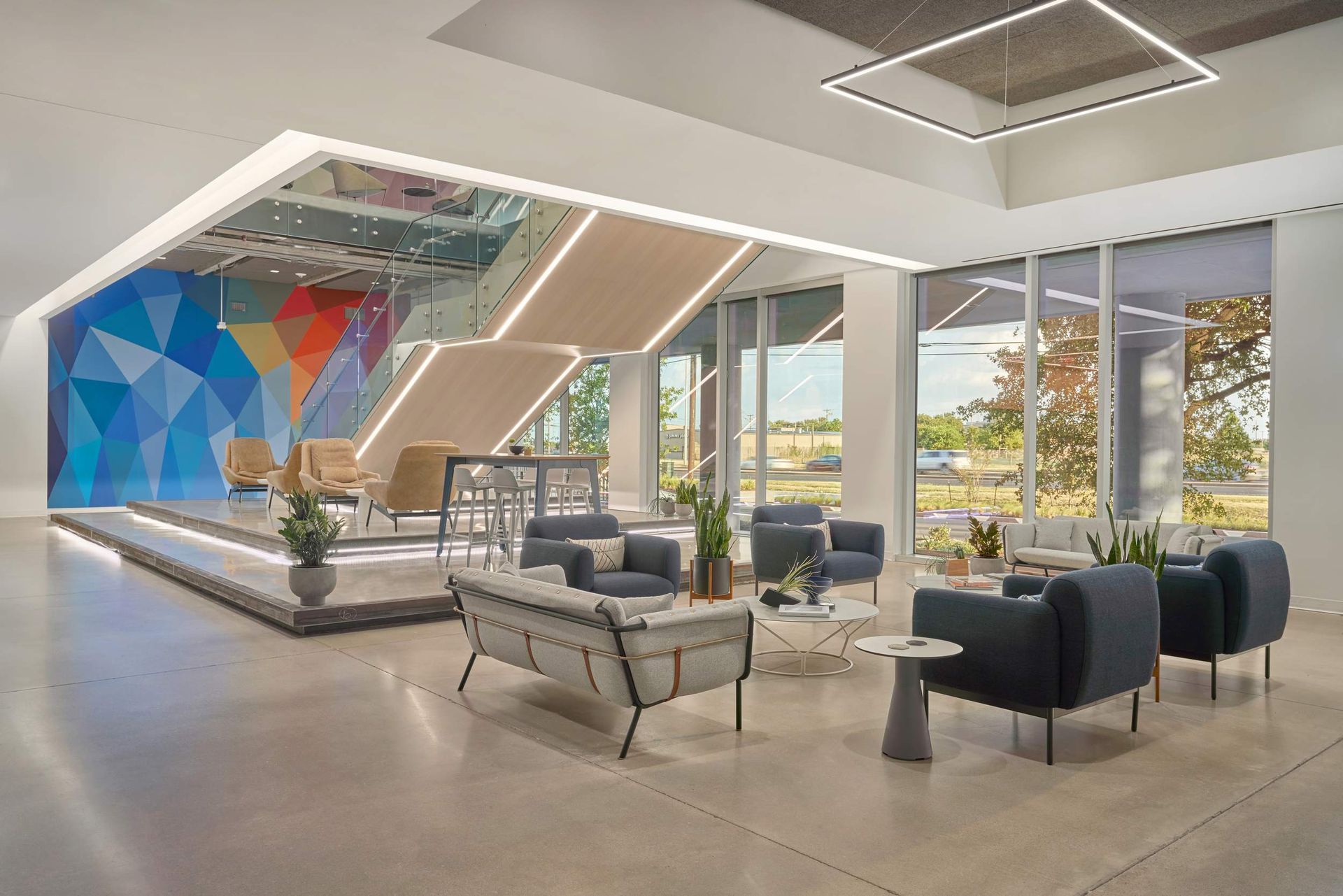 Modern office lobby with seating, geometric wall art, and large windows.