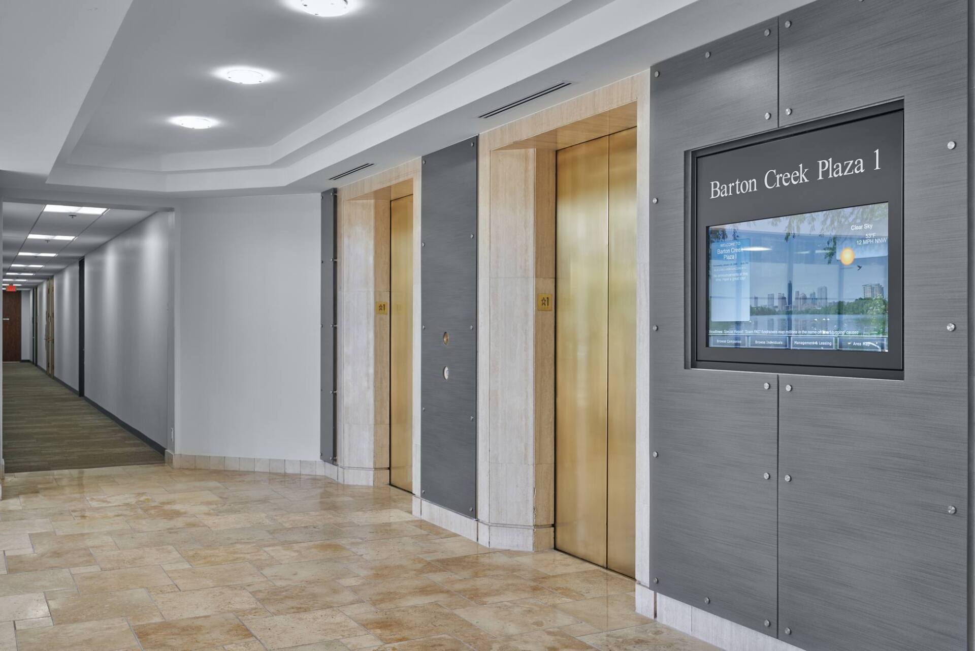 Elevator doors in a building hallway with a directory panel and tiled floor.