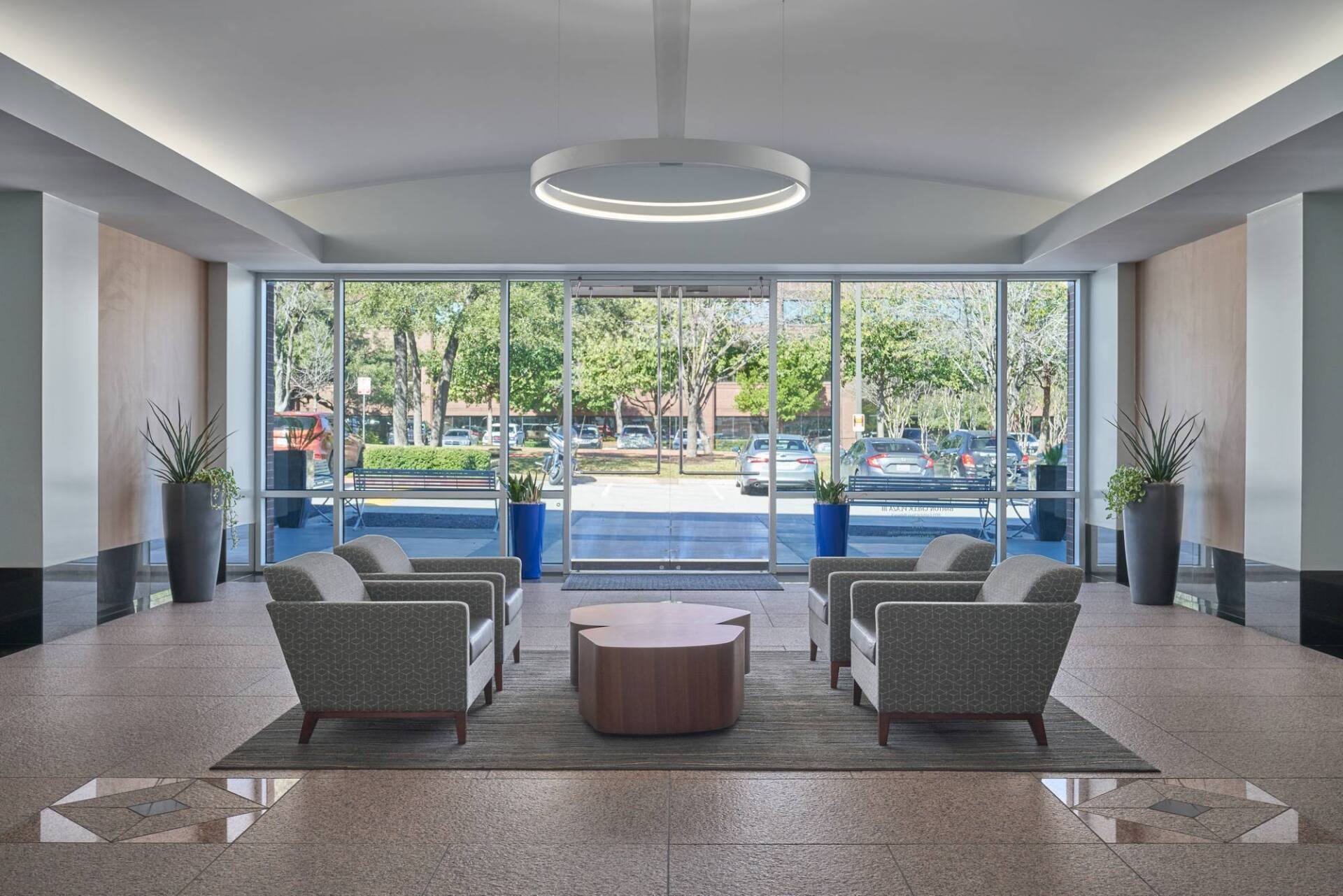 Lobby with seating area, large windows overlooking street with trees, circular light fixture.