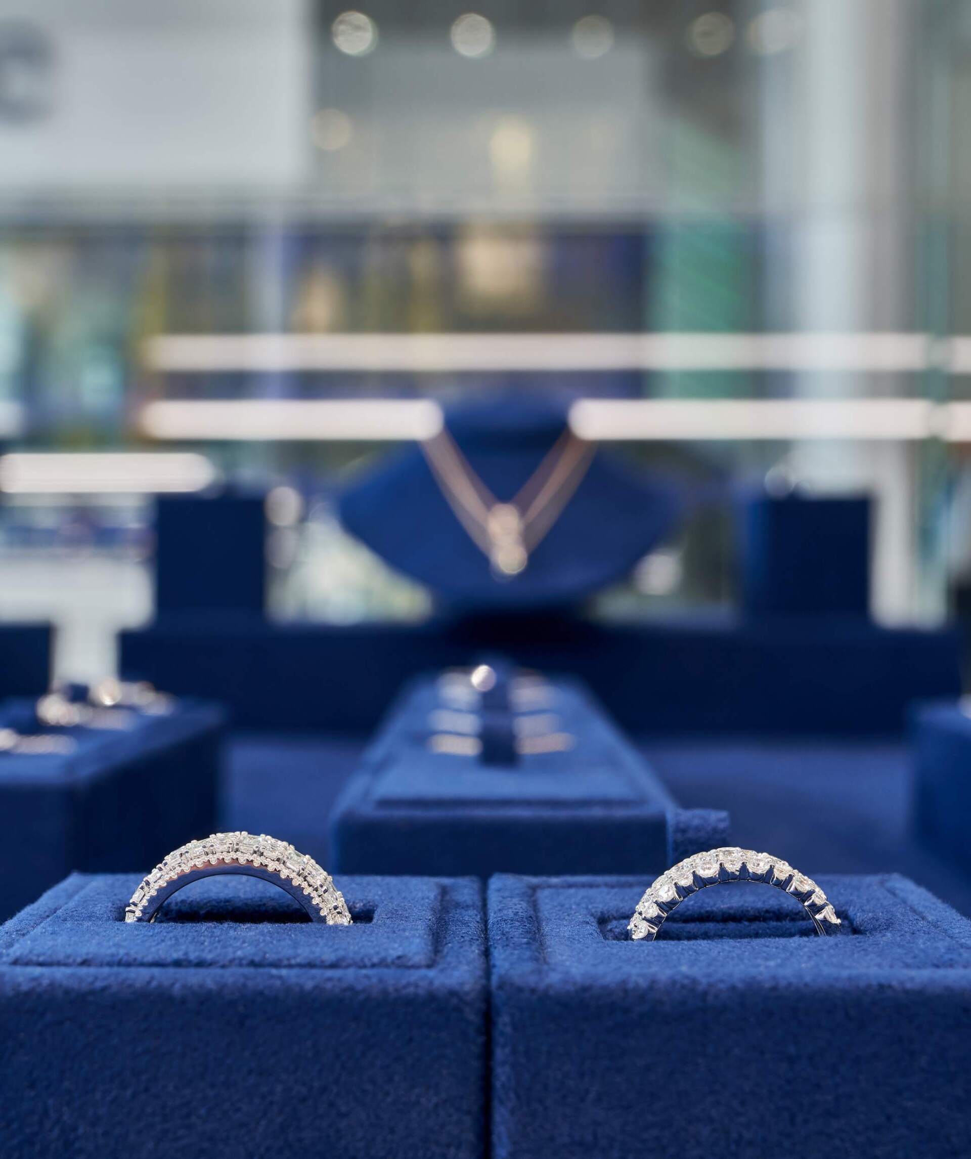 Diamond rings and necklace on display in a jewelry store. Blue velvet display cases.