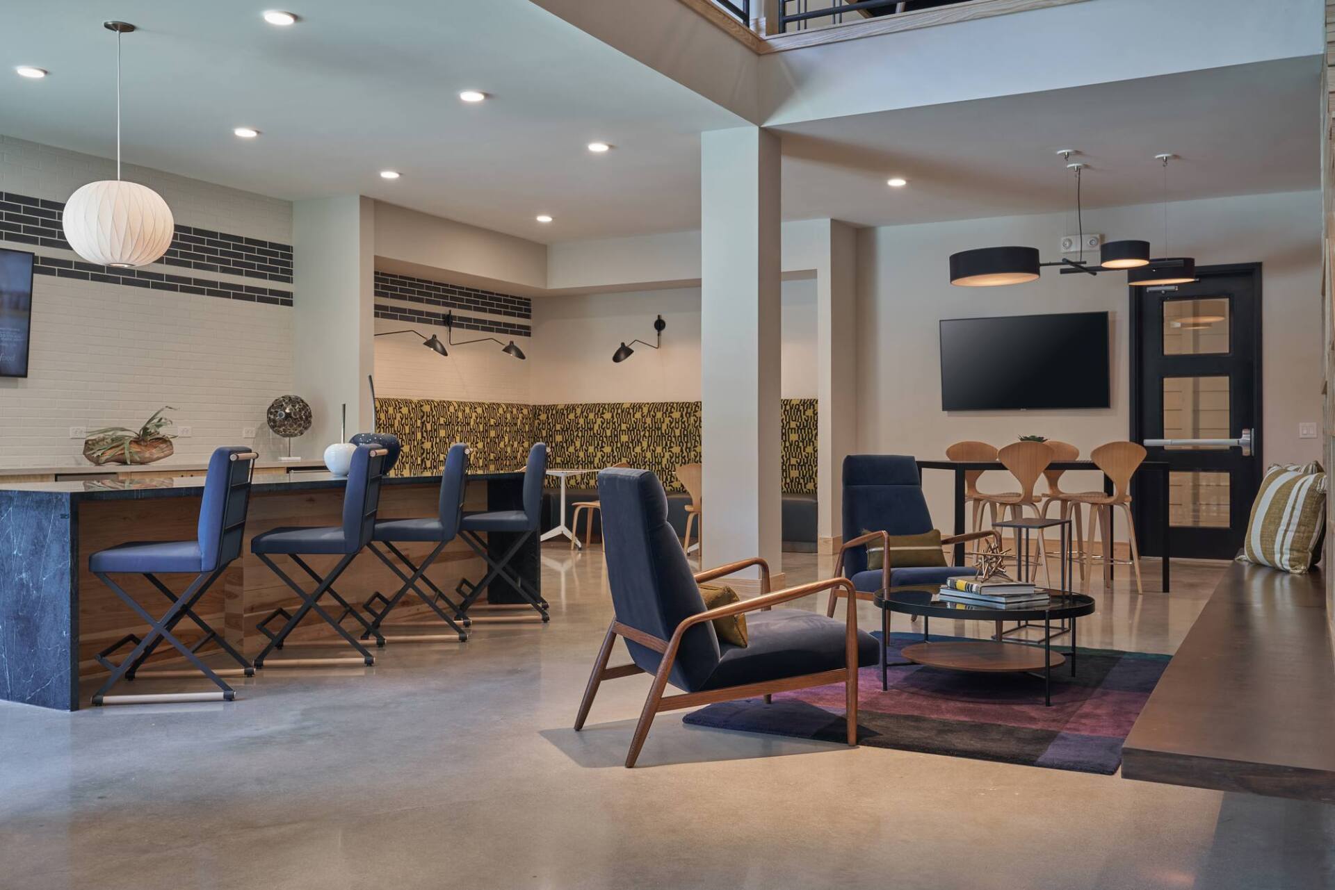 Modern lounge area with a bar, seating, TV, and decorative fireplace.