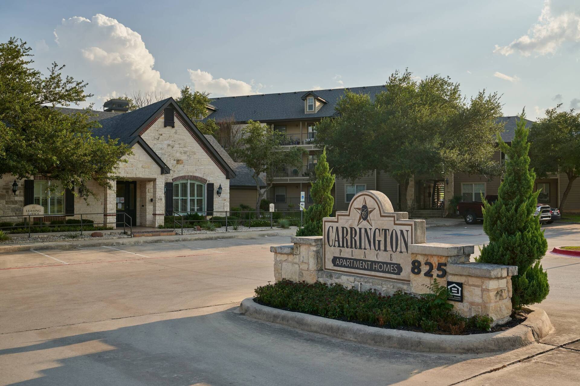 Carrington at Stone Oak sign, 825 address, light stone building, trees, blue sky.
