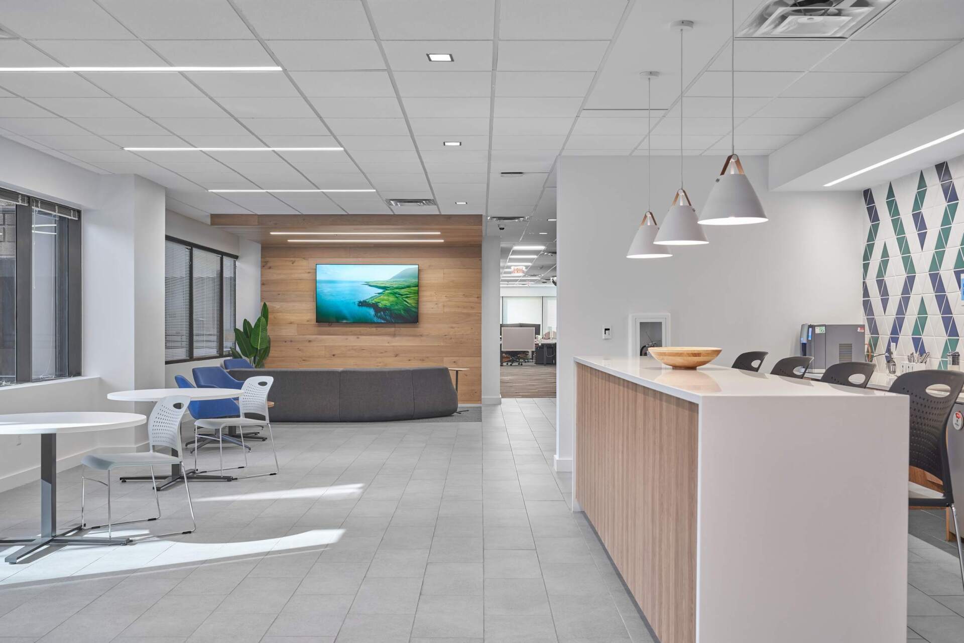 Modern office reception area with white and wood accents, lobby seating, and pendant lights.