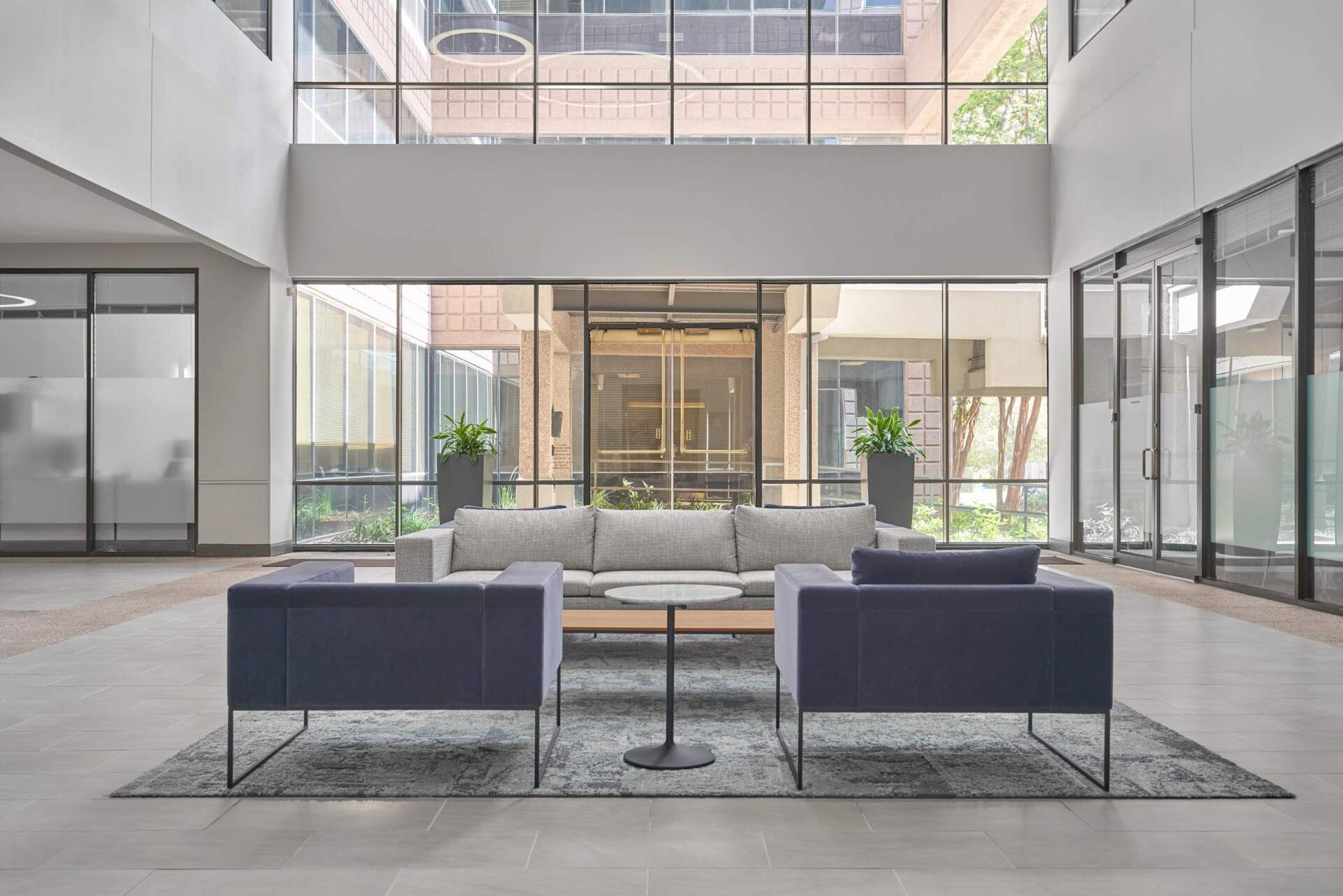 Modern office lobby with couches, rug, and glass windows.