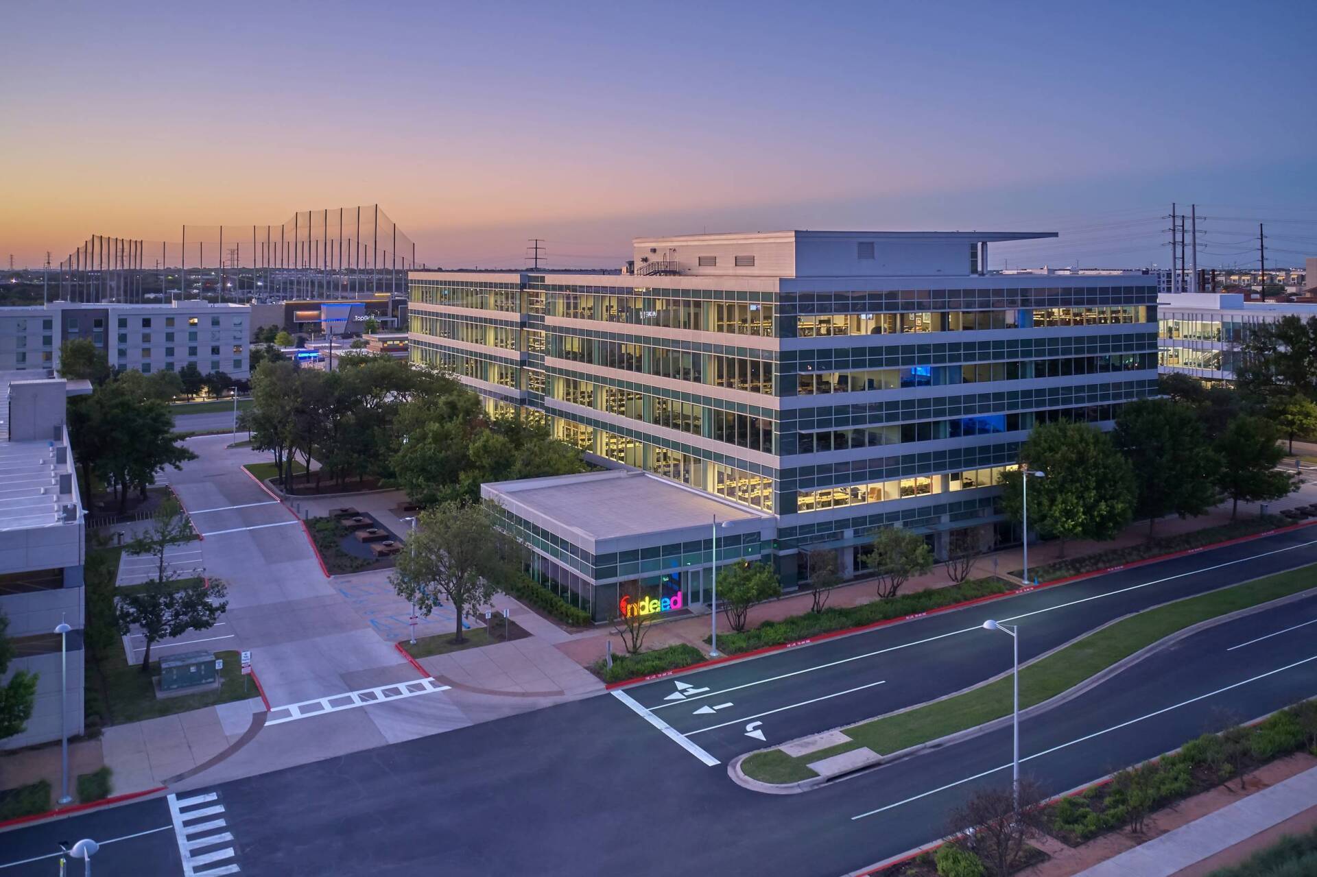 Modern multi-story office building with glass facade, Google logo visible, dusk setting.