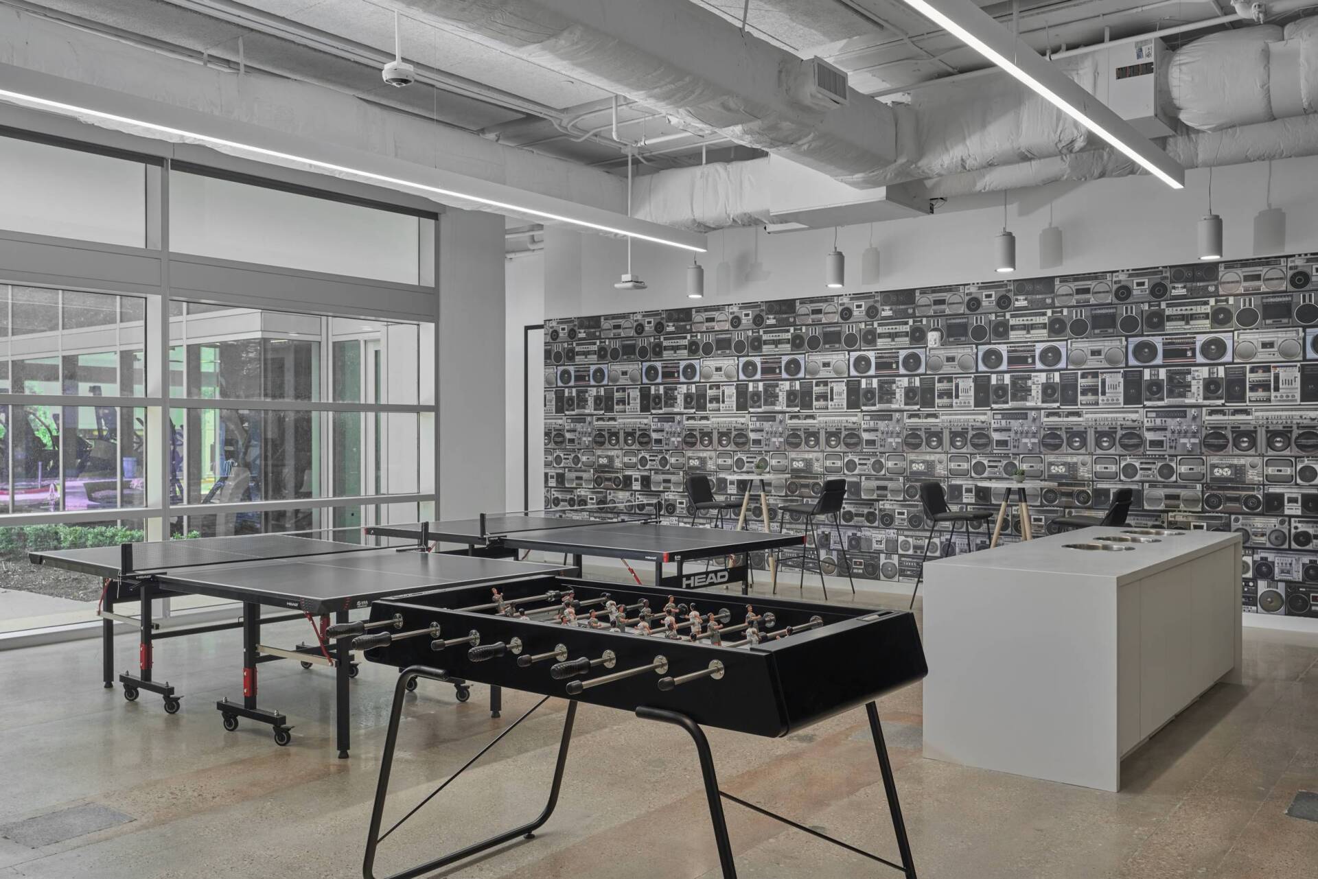 Recreation room with ping pong tables, foosball, and a boombox mural.