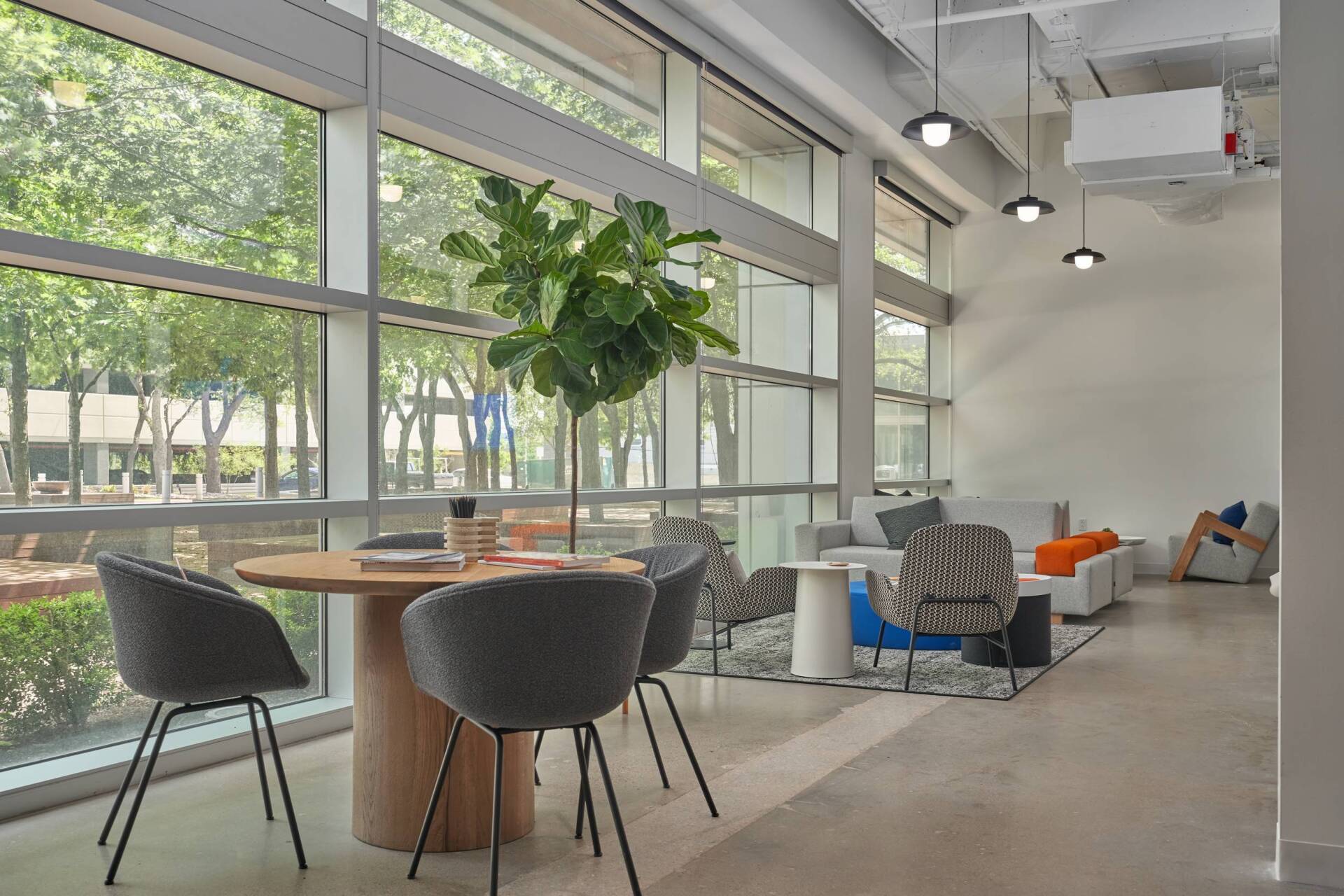 Modern office lounge with round table and chairs, large windows, and seating area.