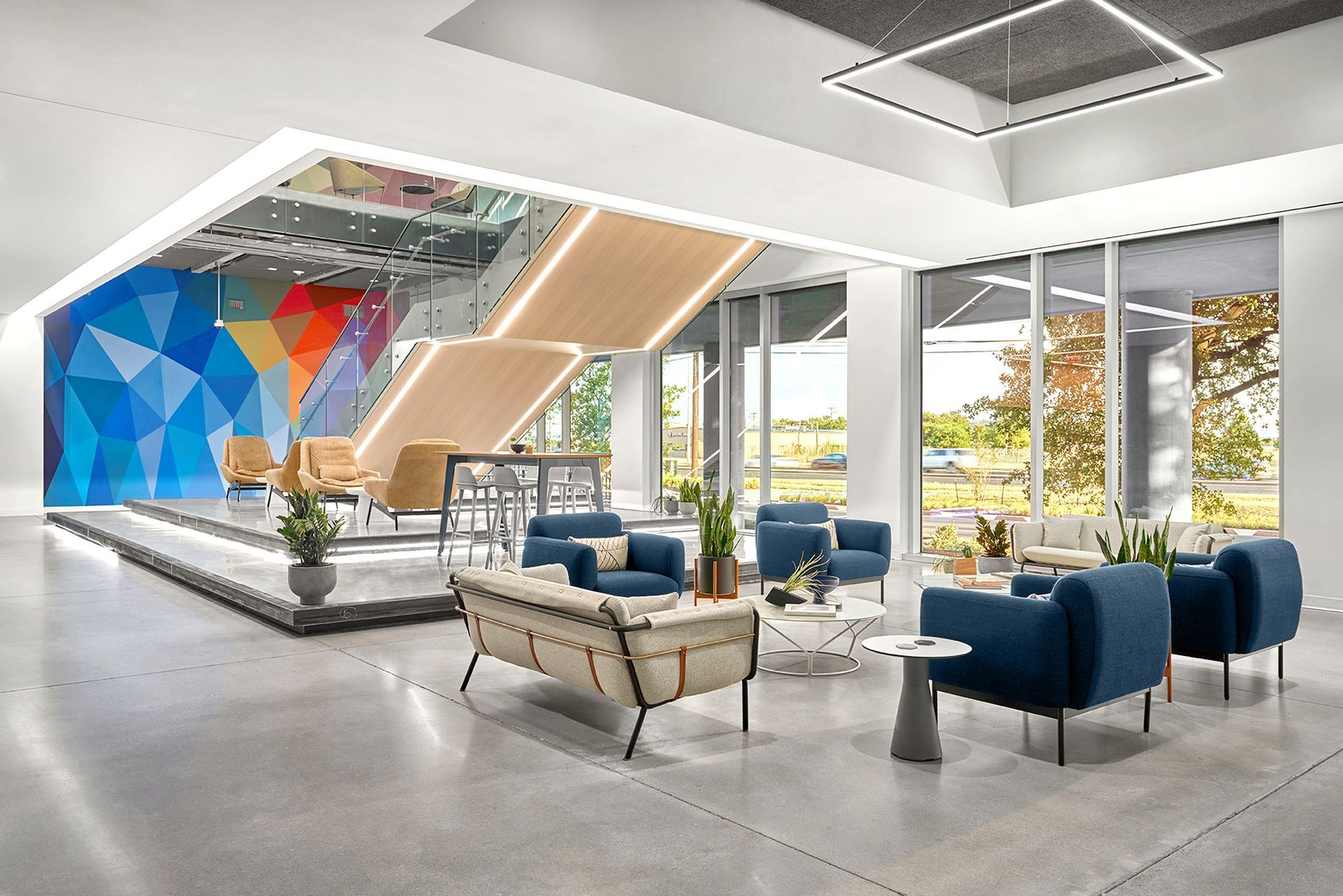 Modern office lobby with blue and tan seating, bright windows, and colorful art.
