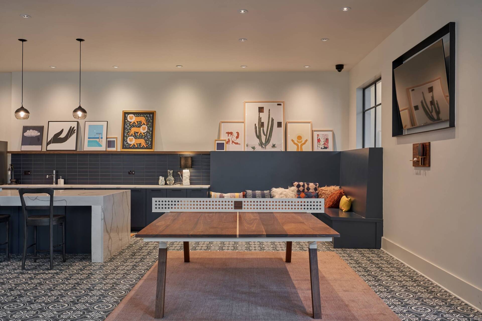 Ping pong table in an entertainment space with a kitchen, art, and seating area.