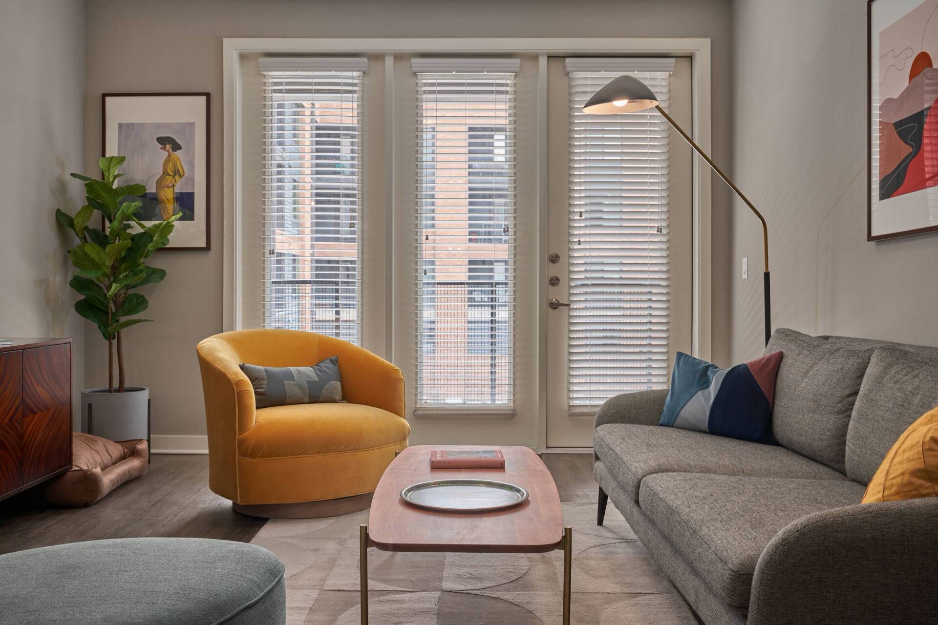 Cozy living room with yellow armchair, gray sofa, and modern decor near a balcony.