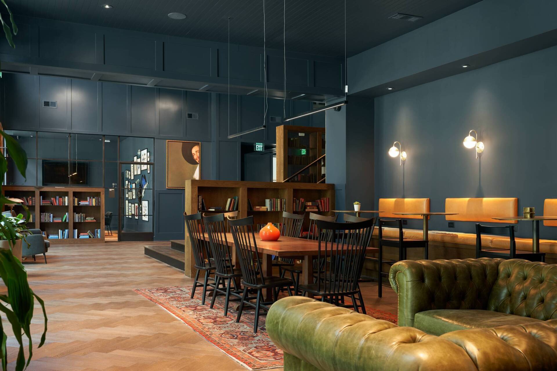 Interior lounge with dark teal walls, seating, and wooden furniture.