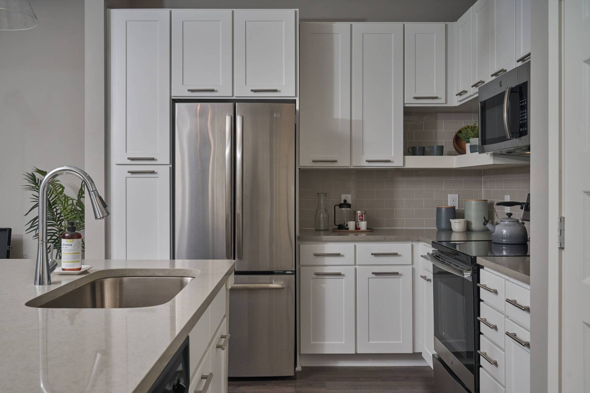 Modern kitchen with white cabinets, stainless steel appliances, and a gray countertop.