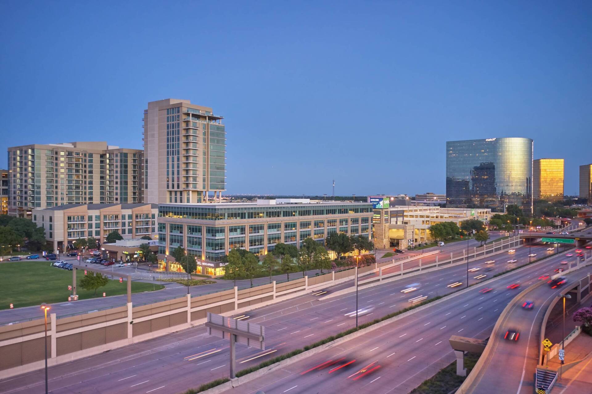 City skyline at dusk with buildings and highway traffic.