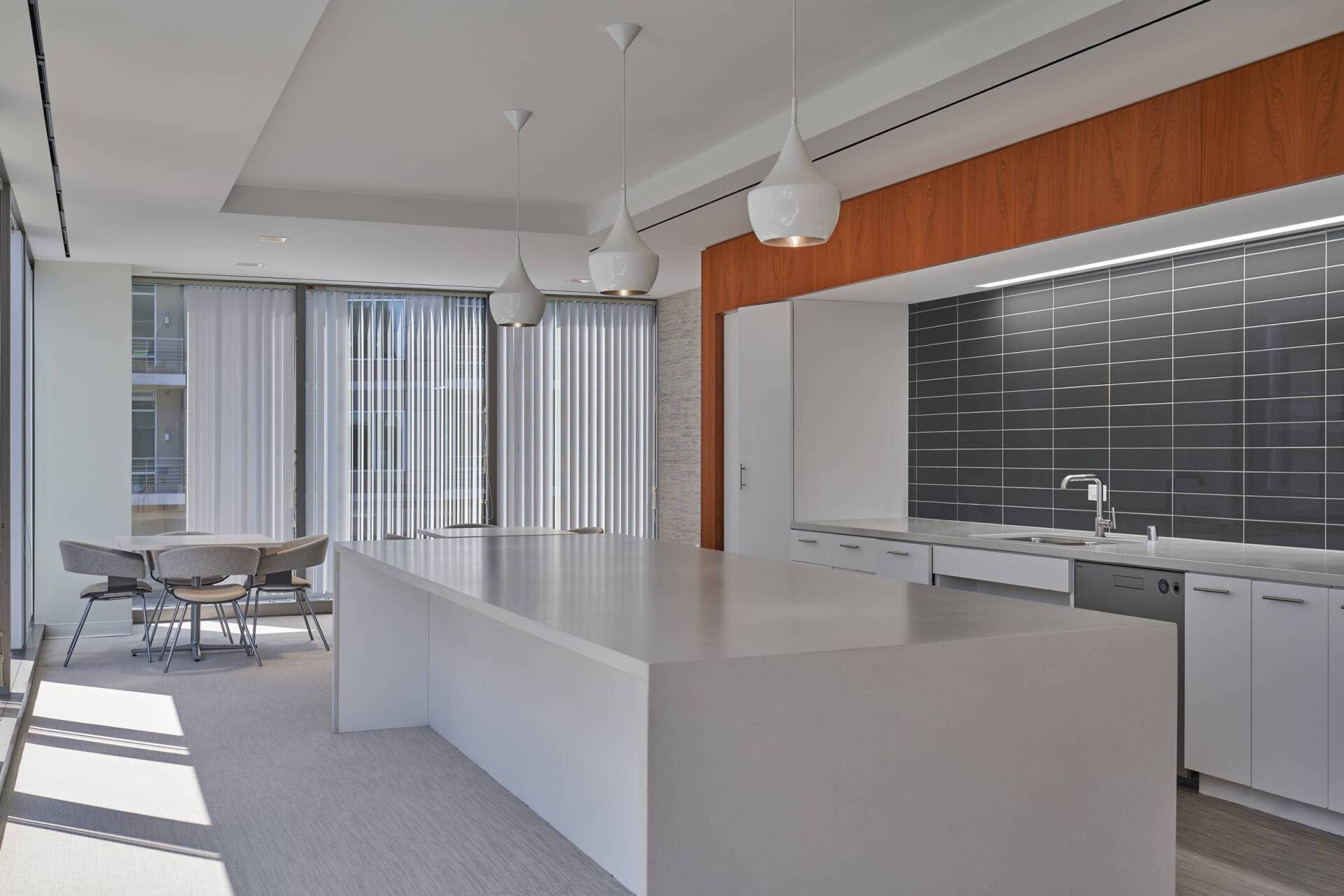 Modern kitchen with white island, pendant lights, and stainless steel appliances; wood-paneled accent wall.