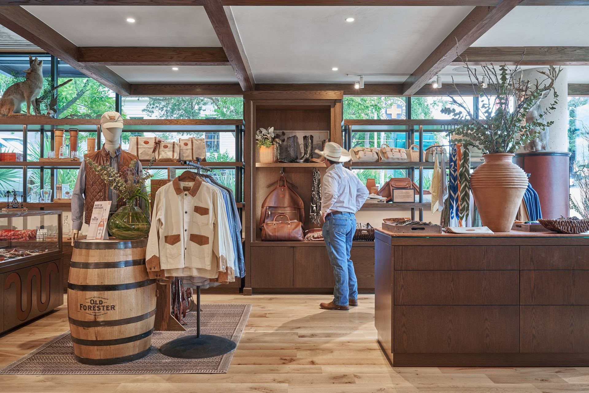A man in a cowboy hat browsing merchandise in a wood-paneled retail store.