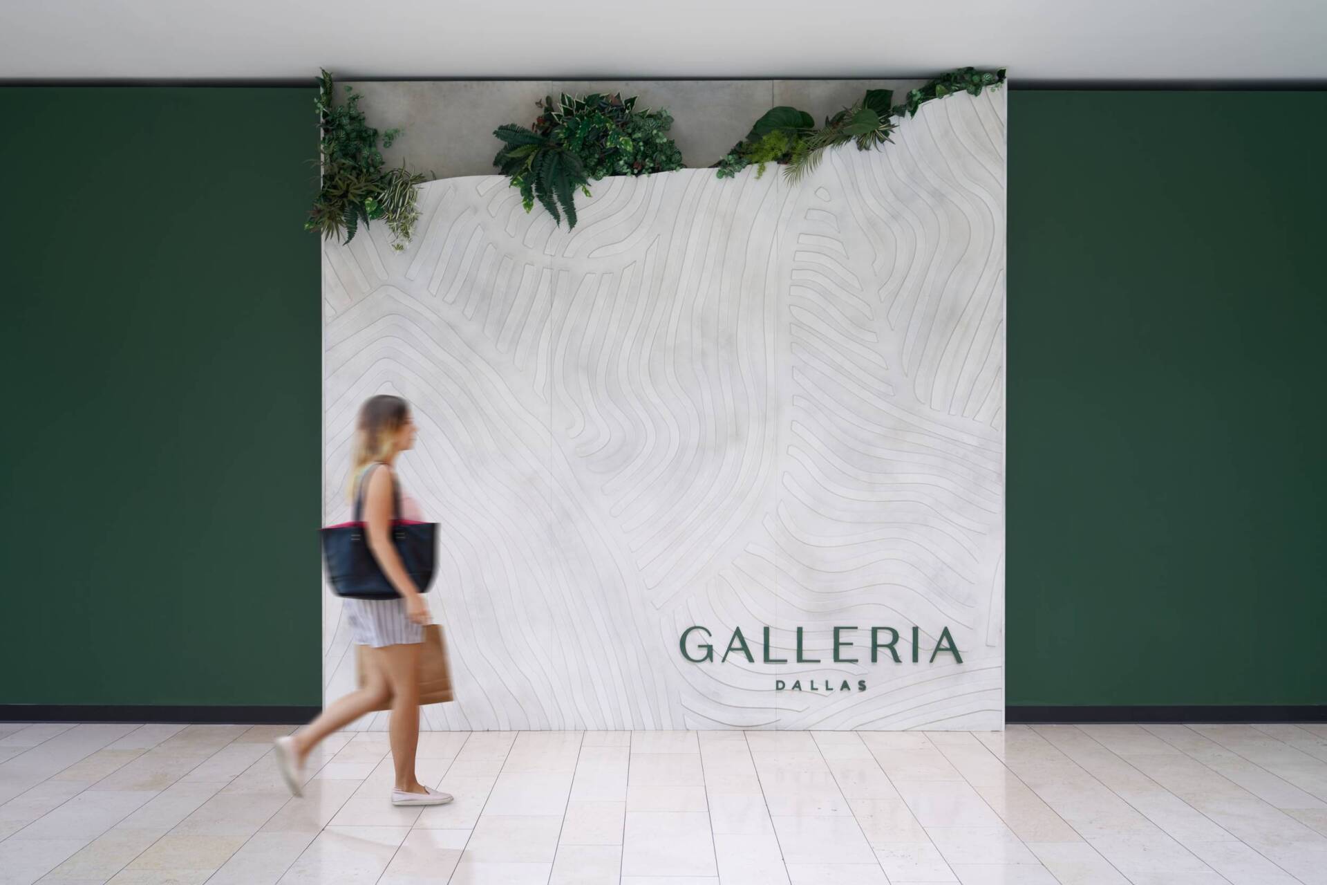 Woman walking past a textured white wall with