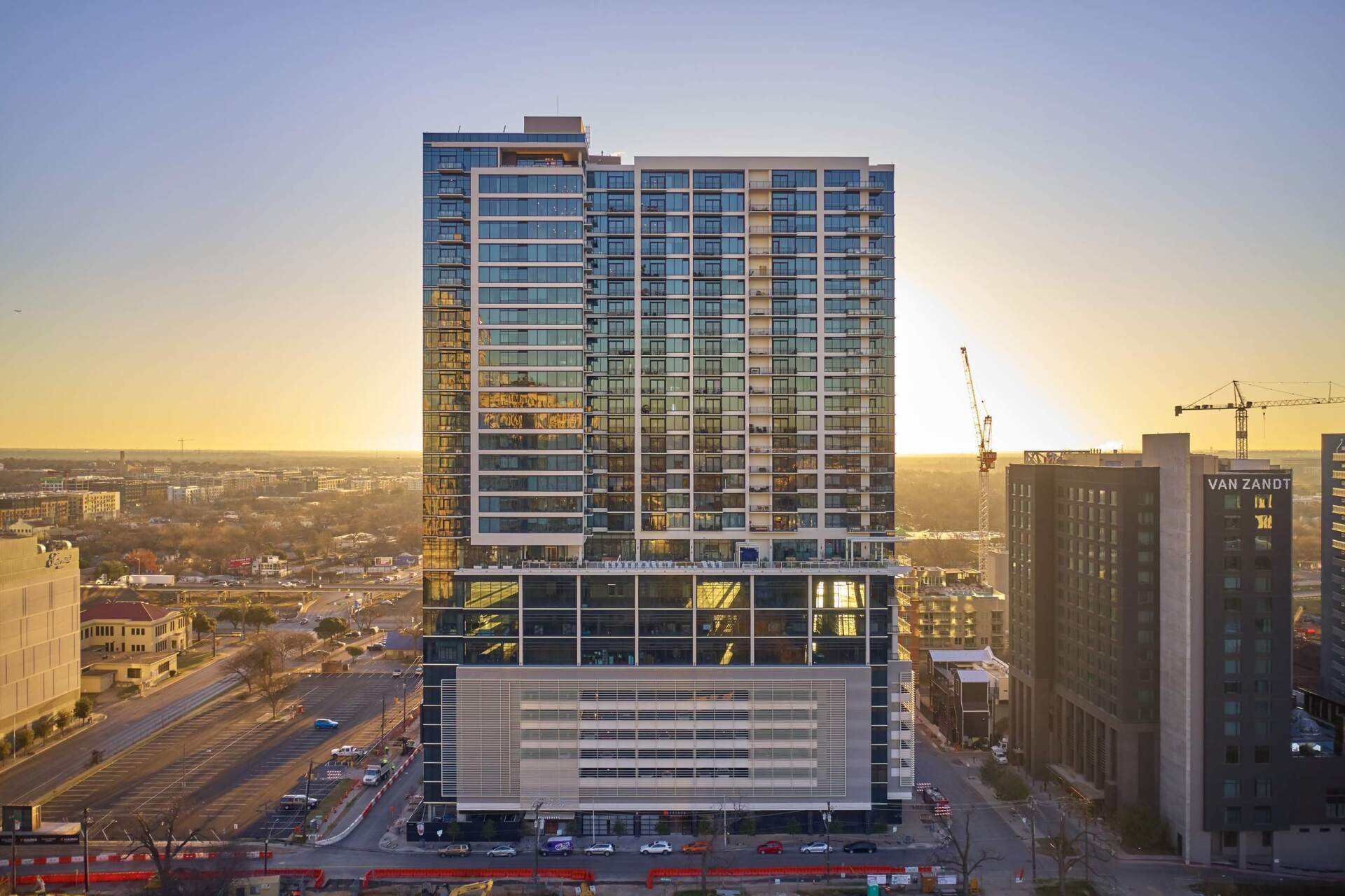 Tall modern high-rise building with many glass windows against a sunset.