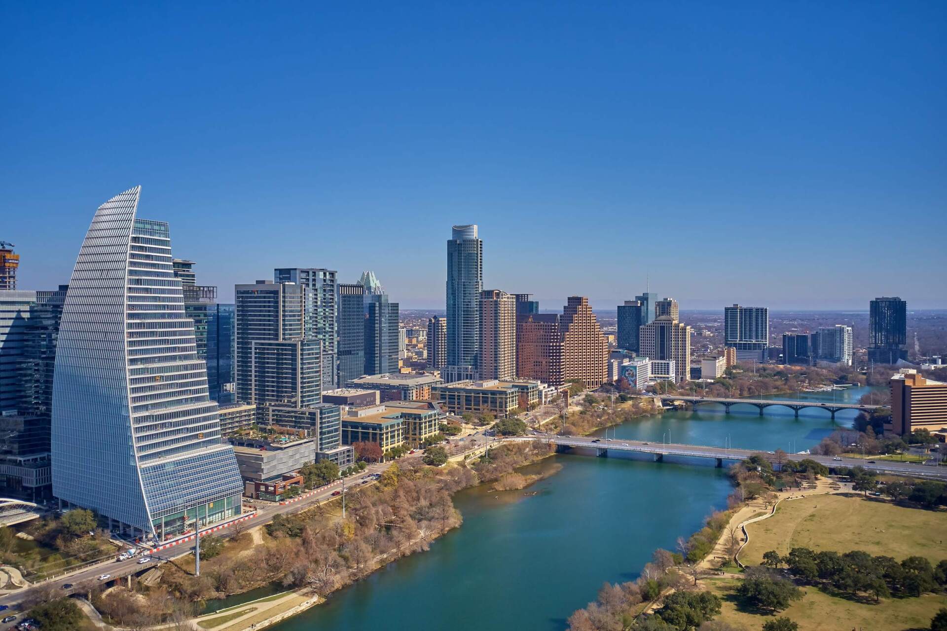 Austin, Texas skyline with river and bridges, under a clear blue sky. Modern high-rise buildings.