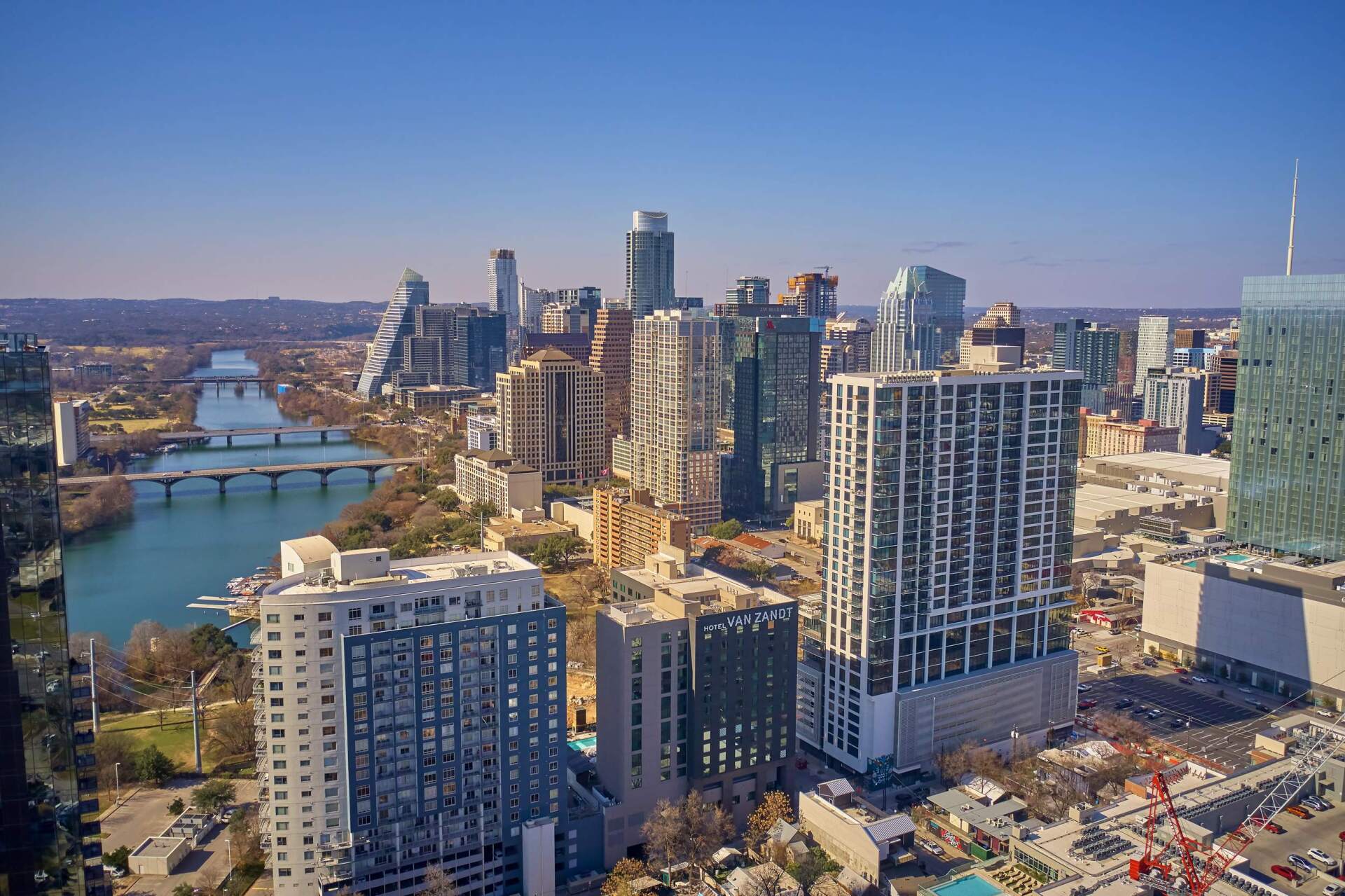 Aerial view of Austin, Texas skyline with skyscrapers, the Colorado River, and a bridge.