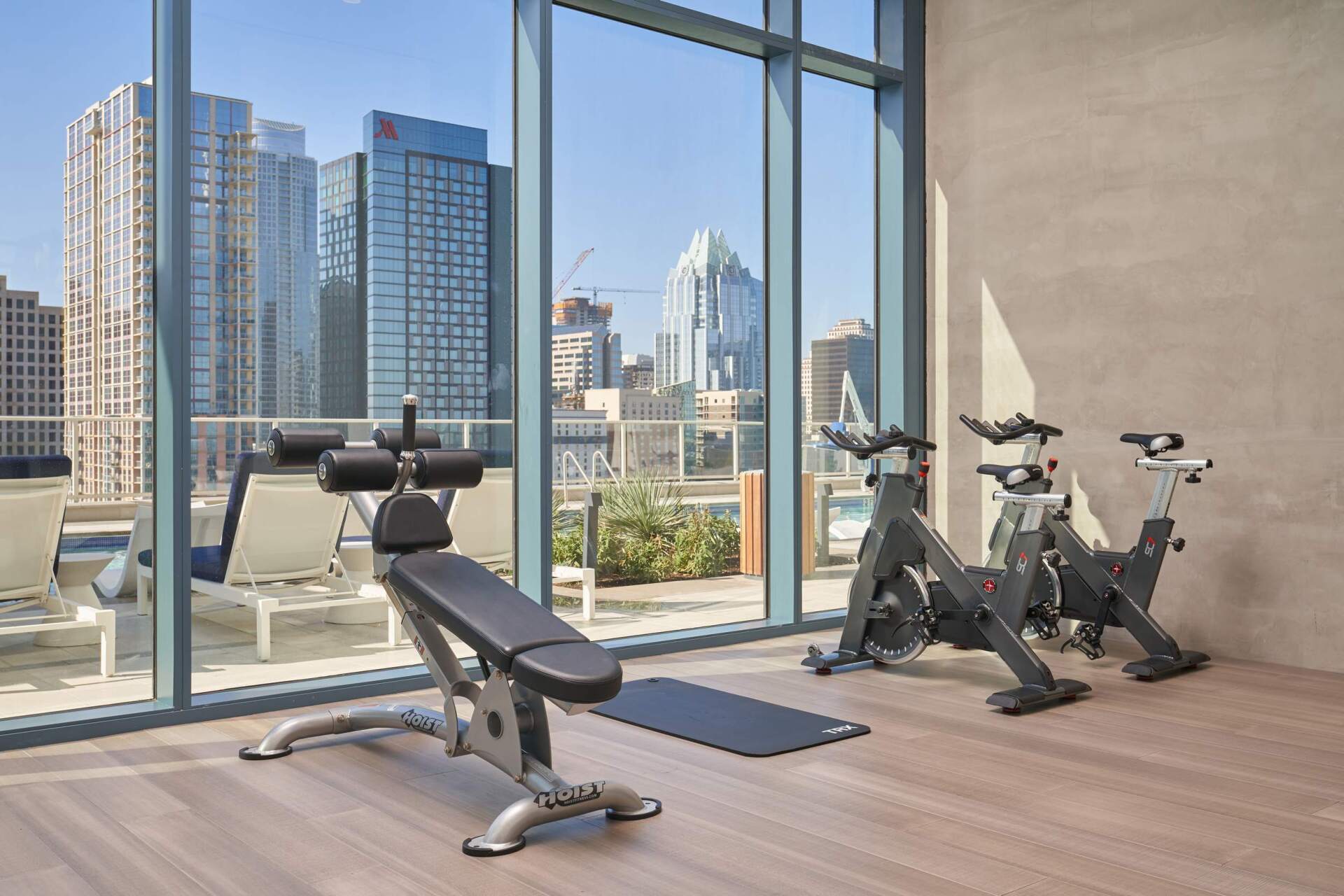 Gym with exercise equipment, large windows, and city skyline view.